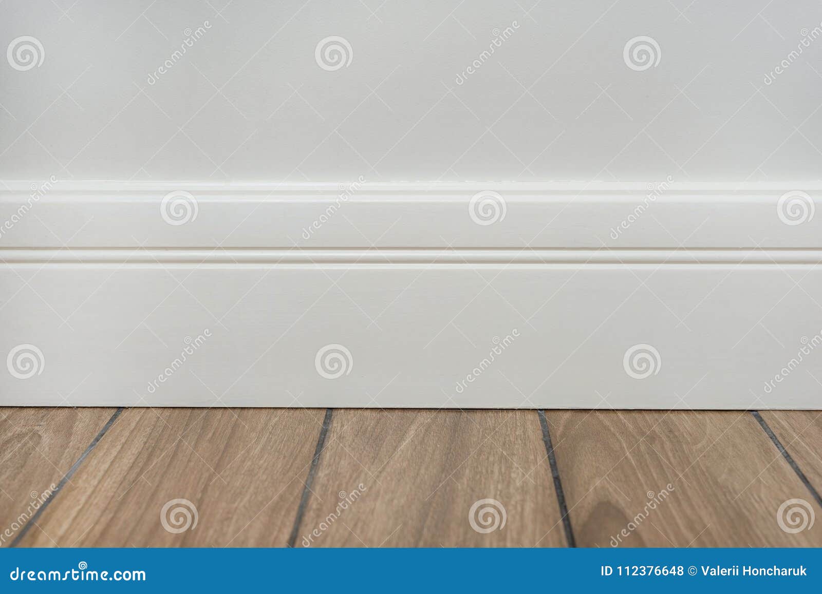 Light Matte Wall, White Baseboard and Tiles Immitating Hardwood