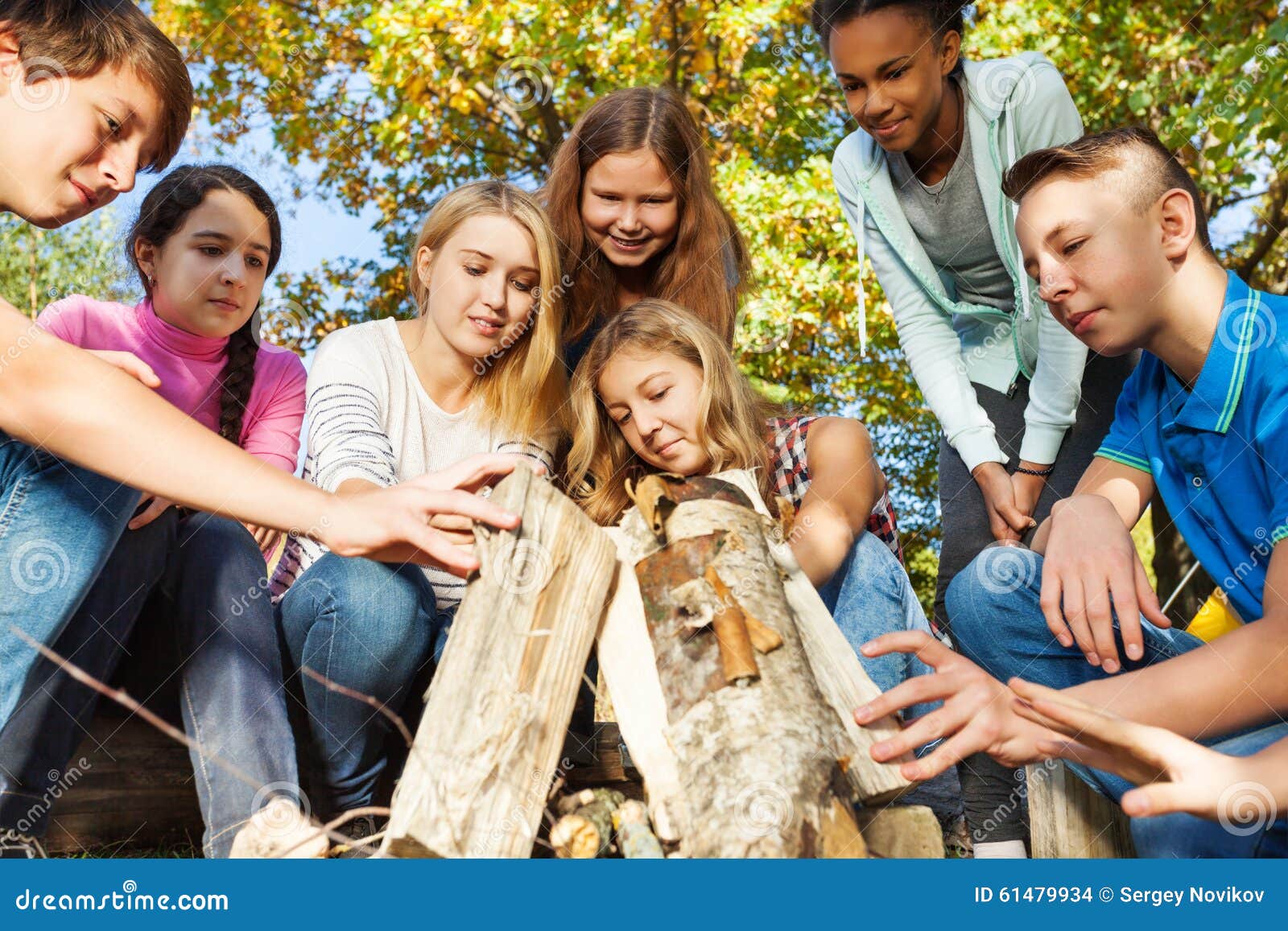 international teens construct bonfire together