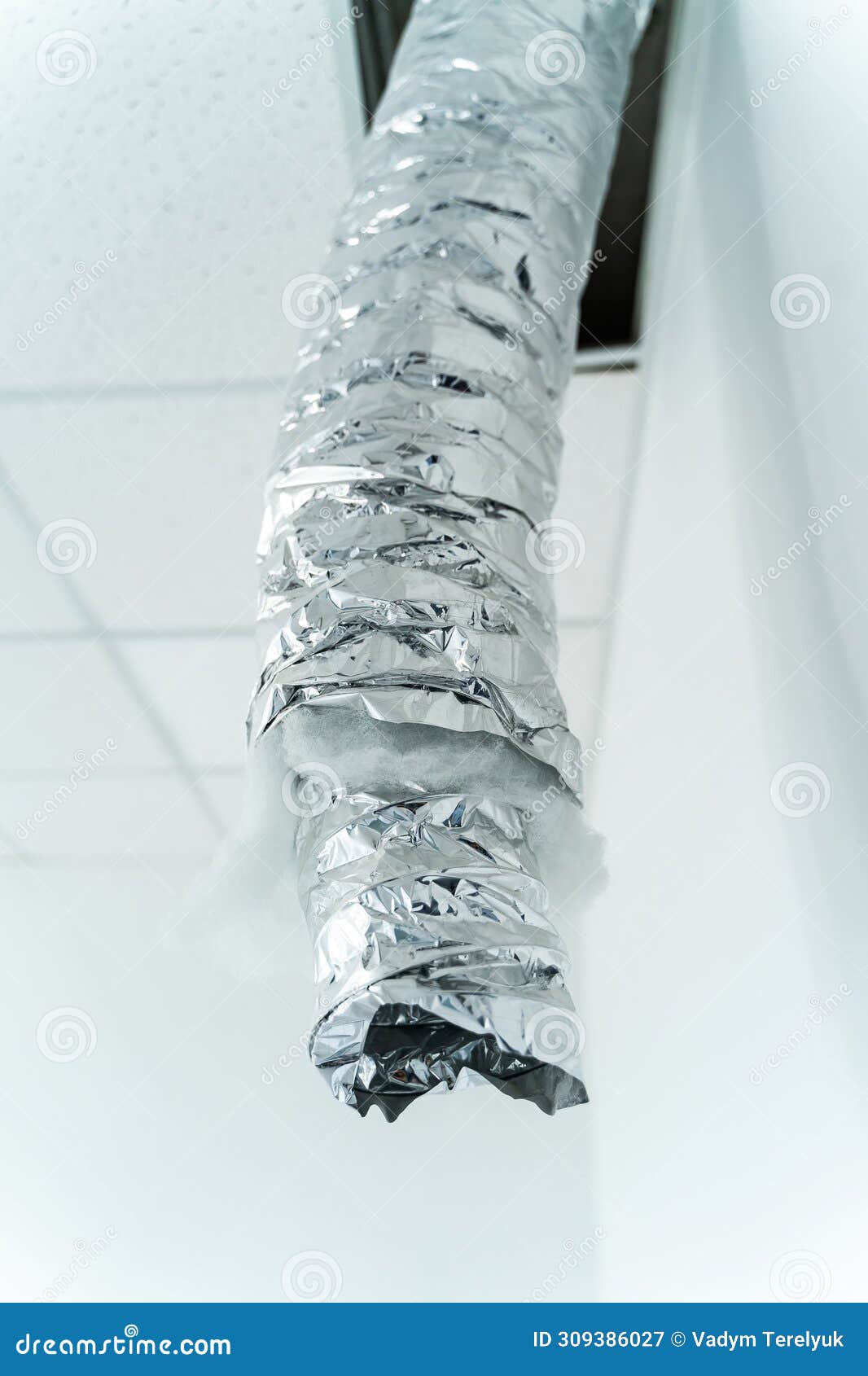 internet cable in foil hangs from the ceiling. empty industrial facility with grey wall. air conditioning tube. closeup