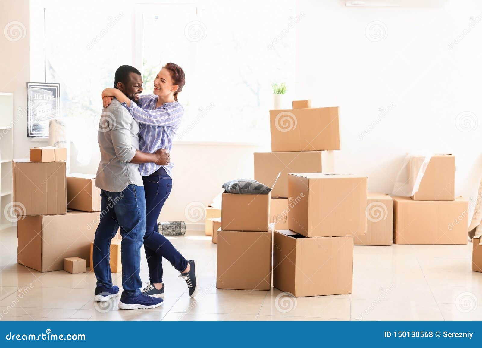 interracial couple with carton boxes in room. moving into new house