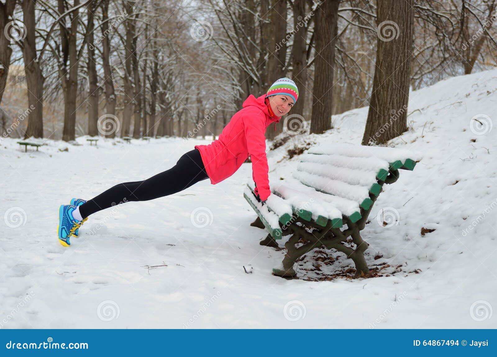 Inverno que corre no parque: corredor feliz da mulher que aquece-se e que exercita antes de movimentar-se na neve, no esporte exterior e no conceito da aptidão