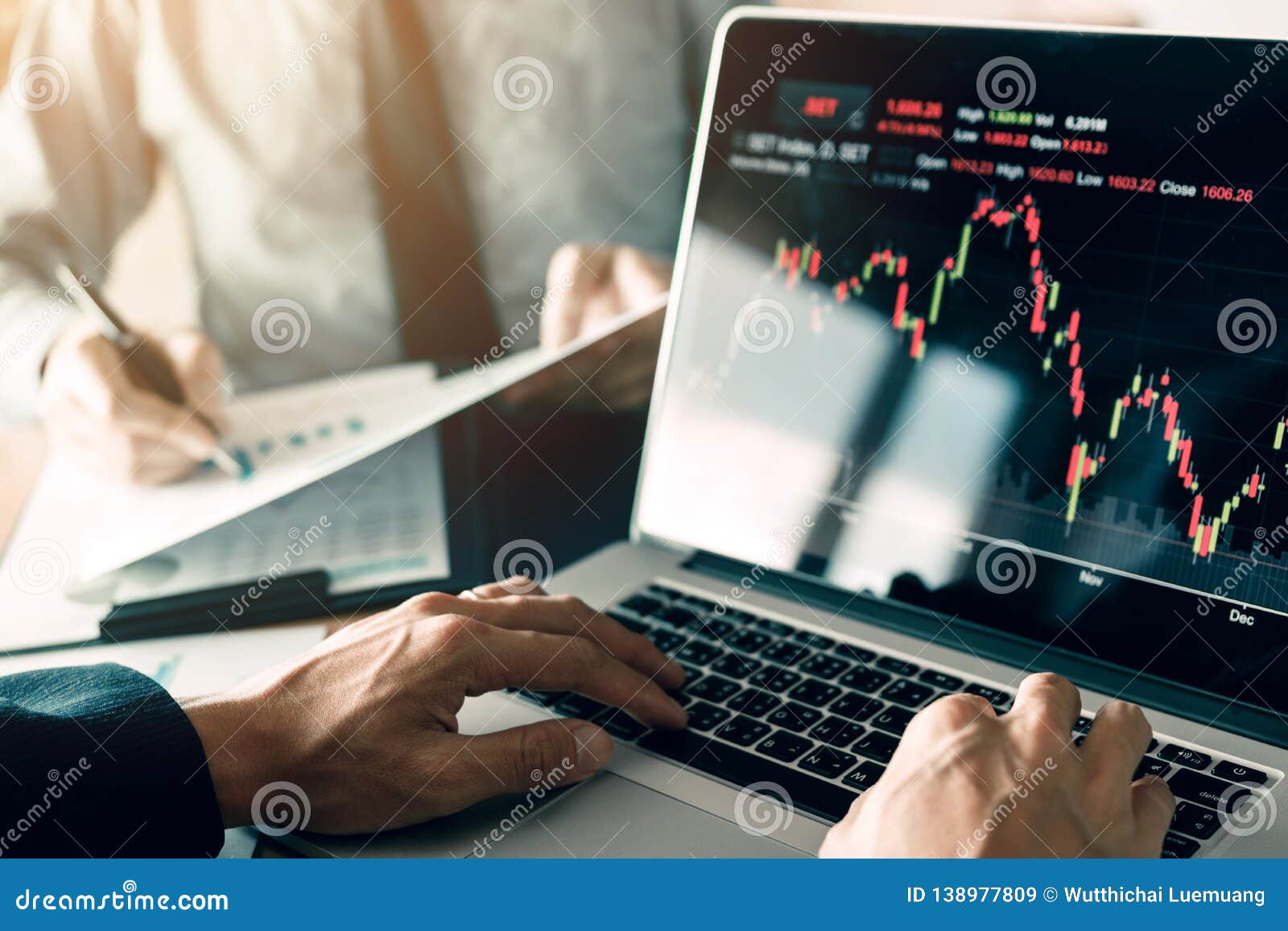 investors are using laptops entering investment websites stocks market and partners are taking notes and analyzing performance