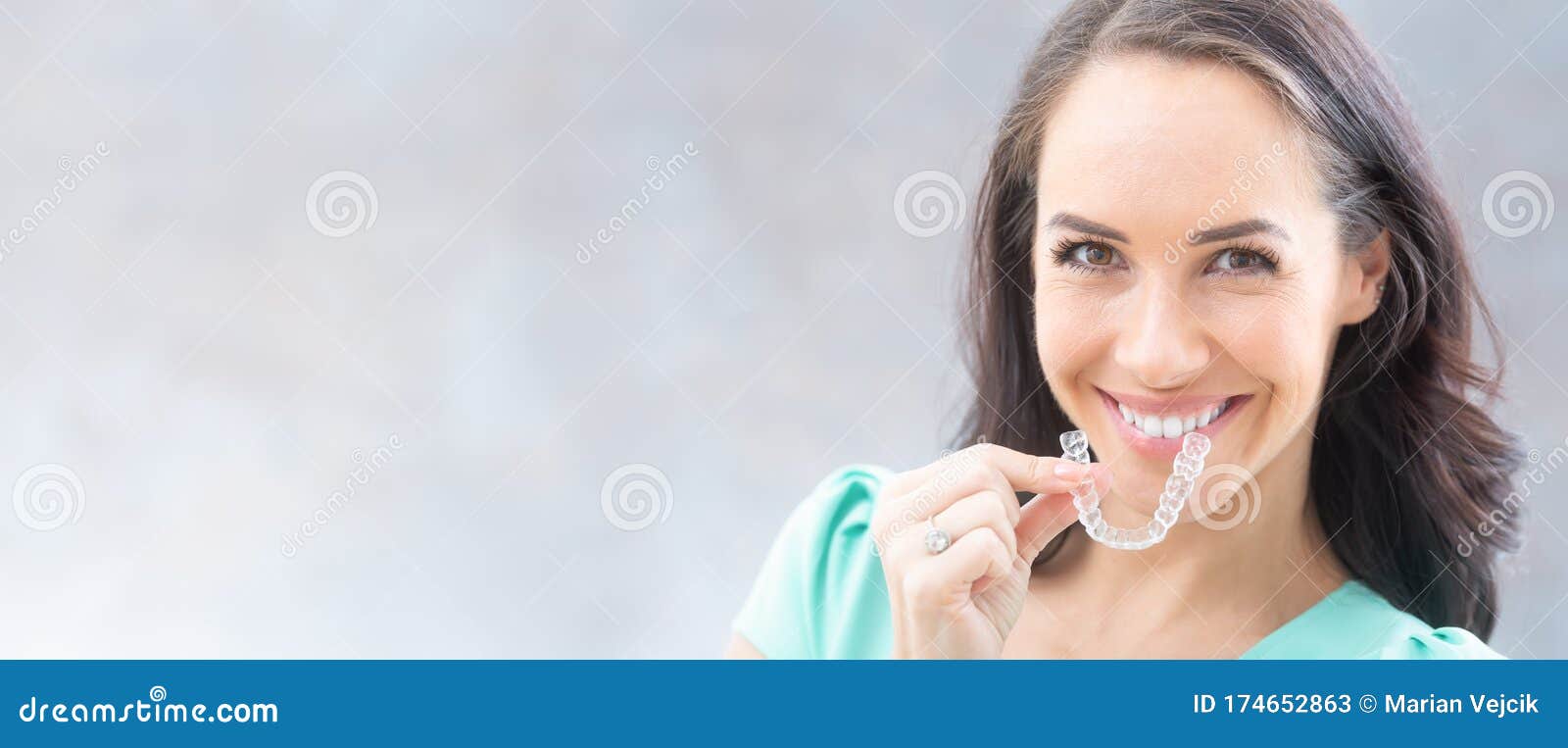 invisalign orthodontics concept - young attractive woman holding - using invisible braces or trainer