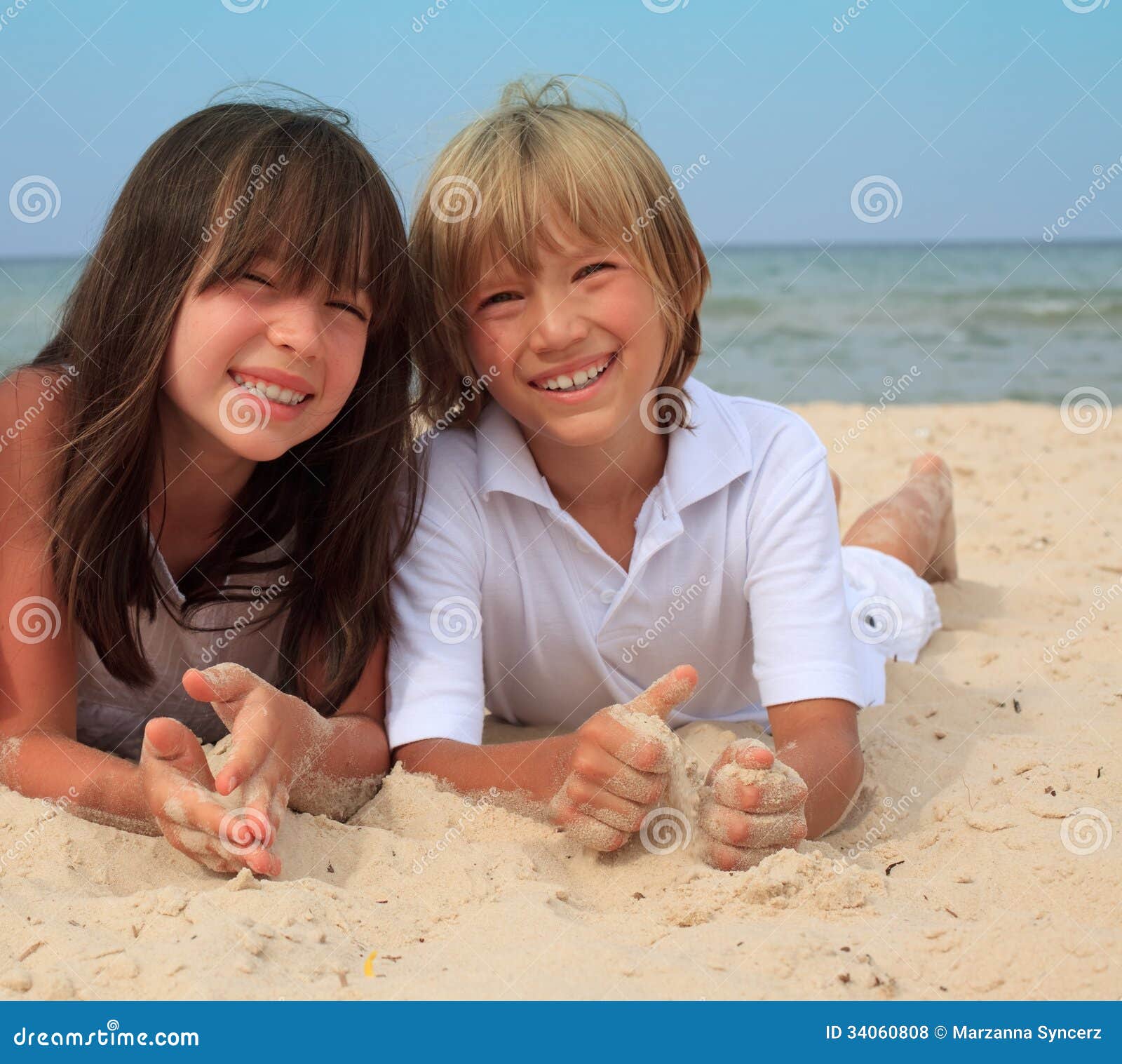 Irmãos na praia. A irmã e o irmão novos colocam junto em uma praia ensolarada.
