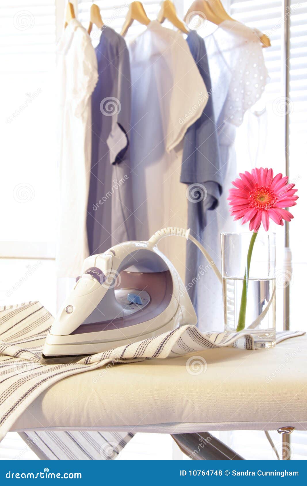 On The Ironing Board Is A Blue Iron And Neatly Folded Ironed Stack Of