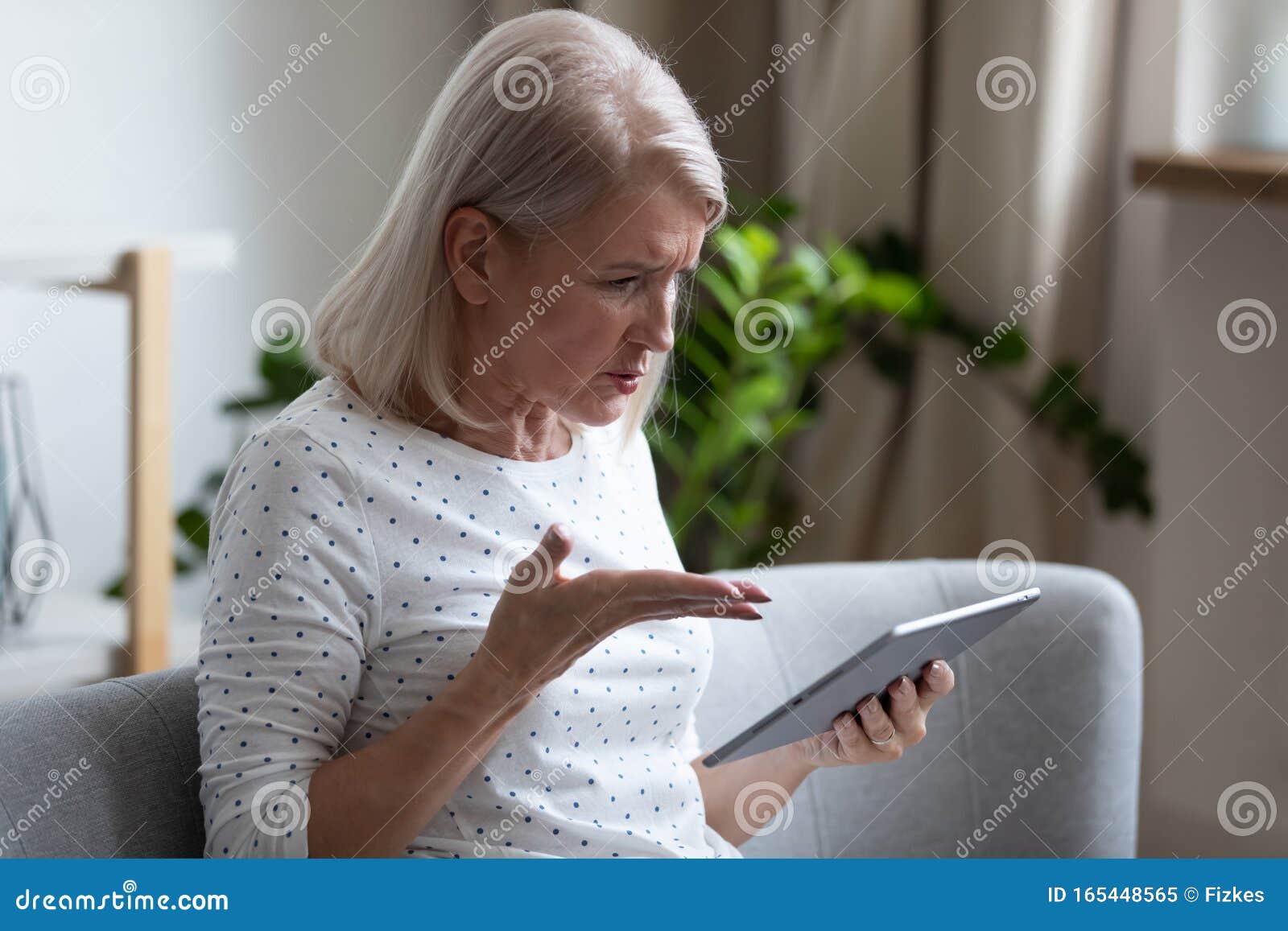 irritated aged woman holding broken tablet having problems with gadget