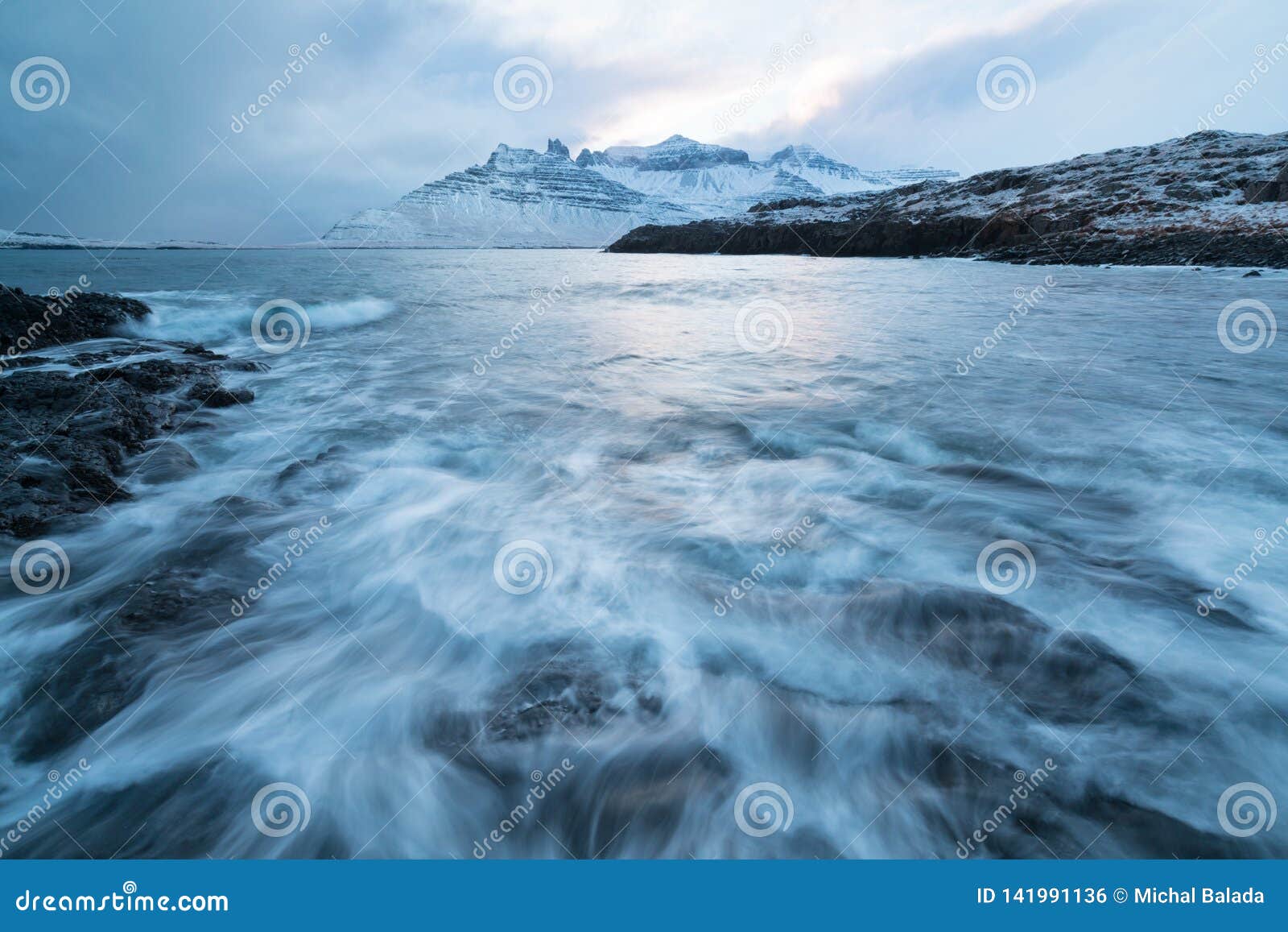 Icelandic winter wild river flowing in the canyon. Wild Icelandic winter river covered in snow and ice. Beautiful sunny day. Arctic landscape background