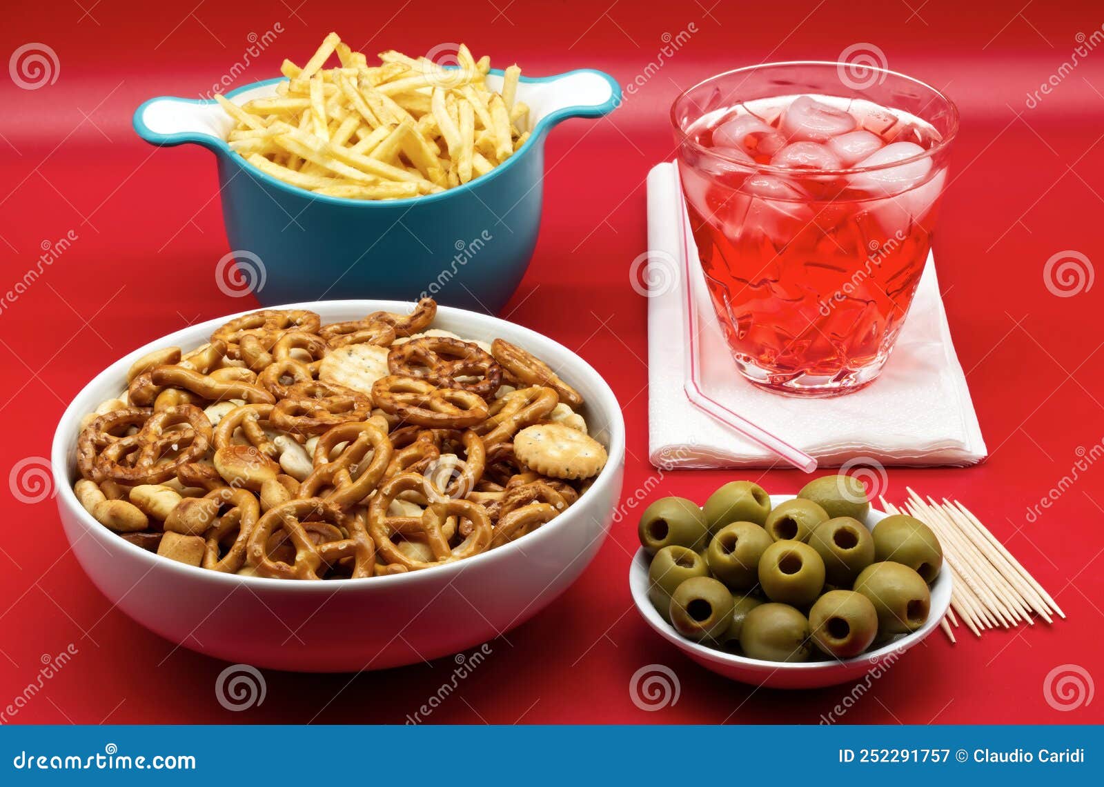 italian aperitive: glass of frozen cocktail with green pitted olves, fries and salted pretzels snack for party