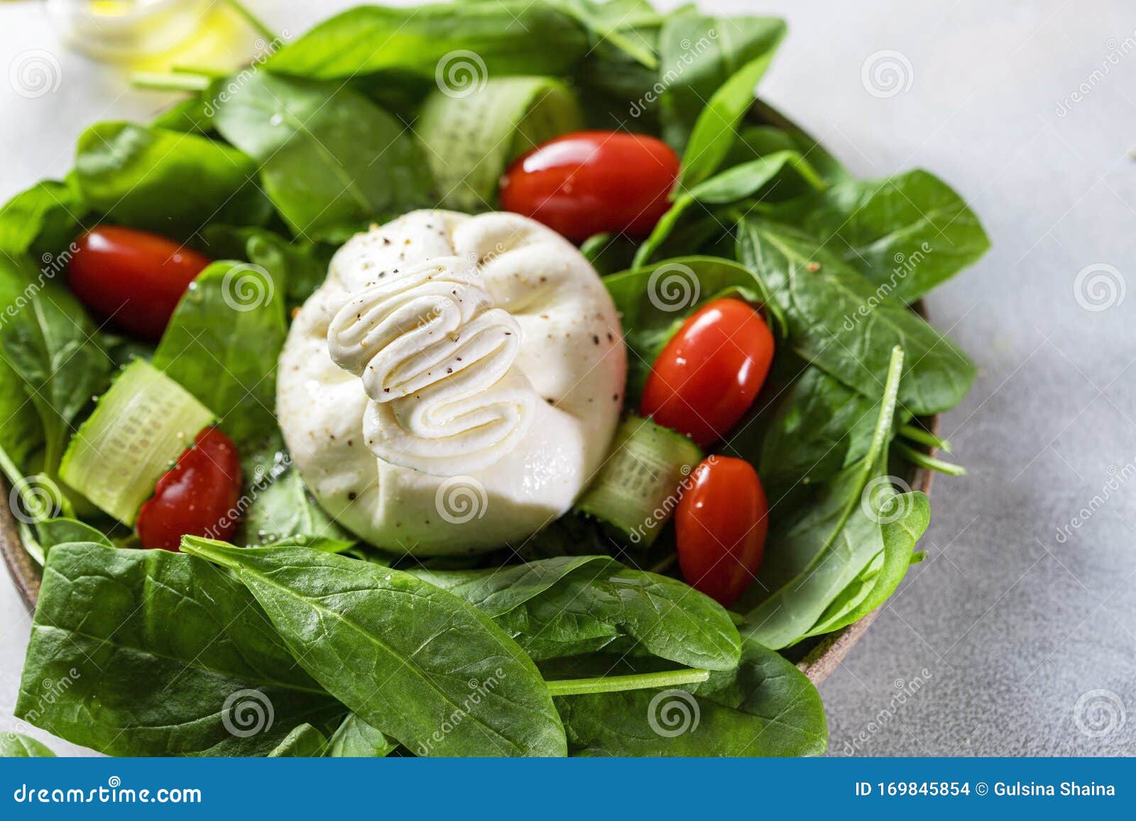 prangende Fruity nedadgående Italian Cheese Burrata with a Salad of Fresh Spinach, Cucumbers and Cherry  Tomatoes with Olive Oil in a Ceramic Plate on a Light Stock Photo - Image  of delicious, dark: 169845854