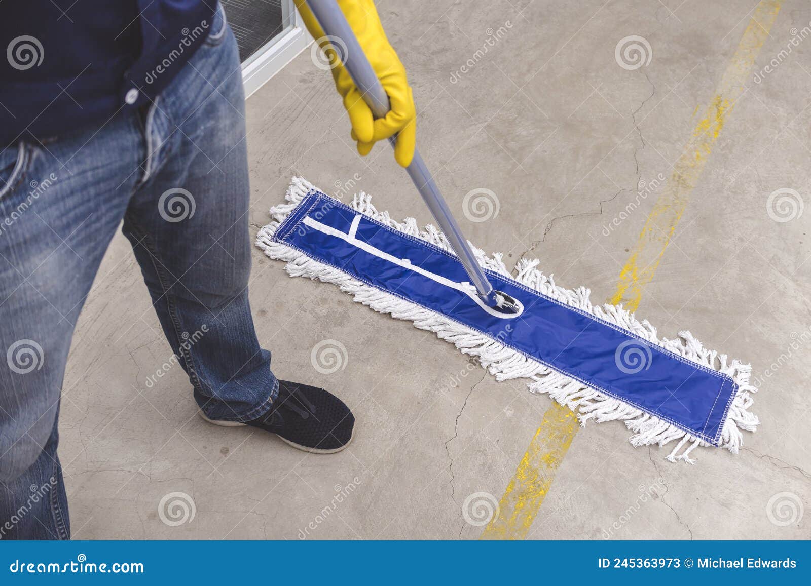 A Janitor Cleans the Surface of the Concrete Floor of a Factory with a