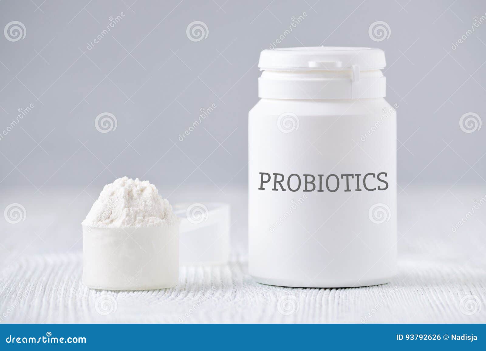 a jar and spoon with probiotic powder on gray