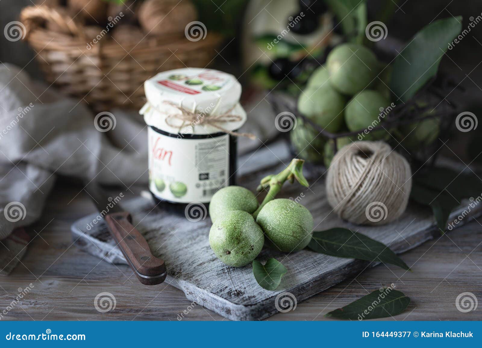 Jar of Walnut Jam on a Wooden Table and a Group of Green Walnuts Stock