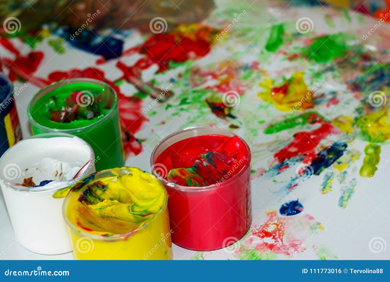 Jars with Multicolored Finger Paints on the Background of Children`s