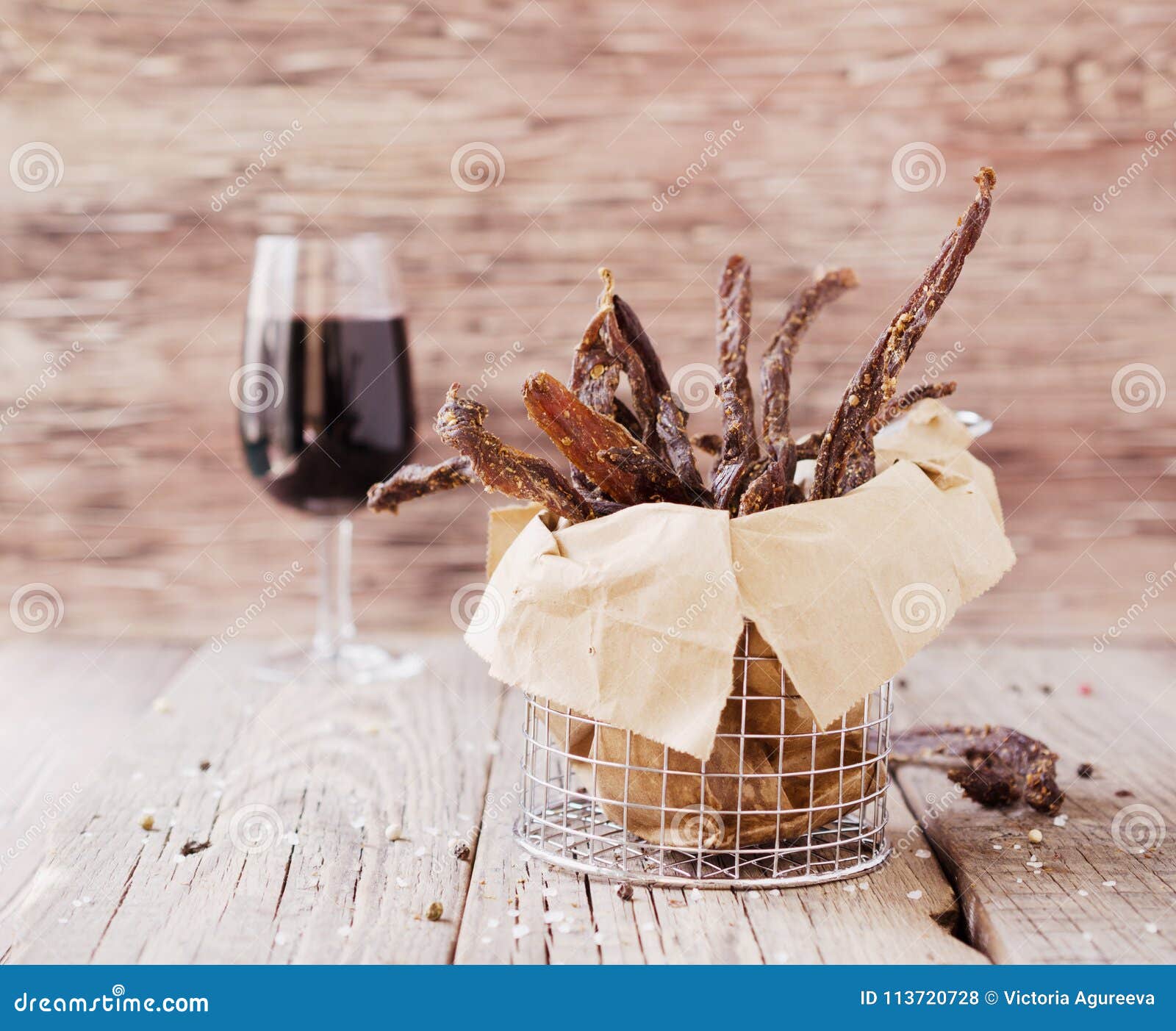 jerked meat, cow, deer, wild beast or biltong with wine bowls on a rustic table, selective focus