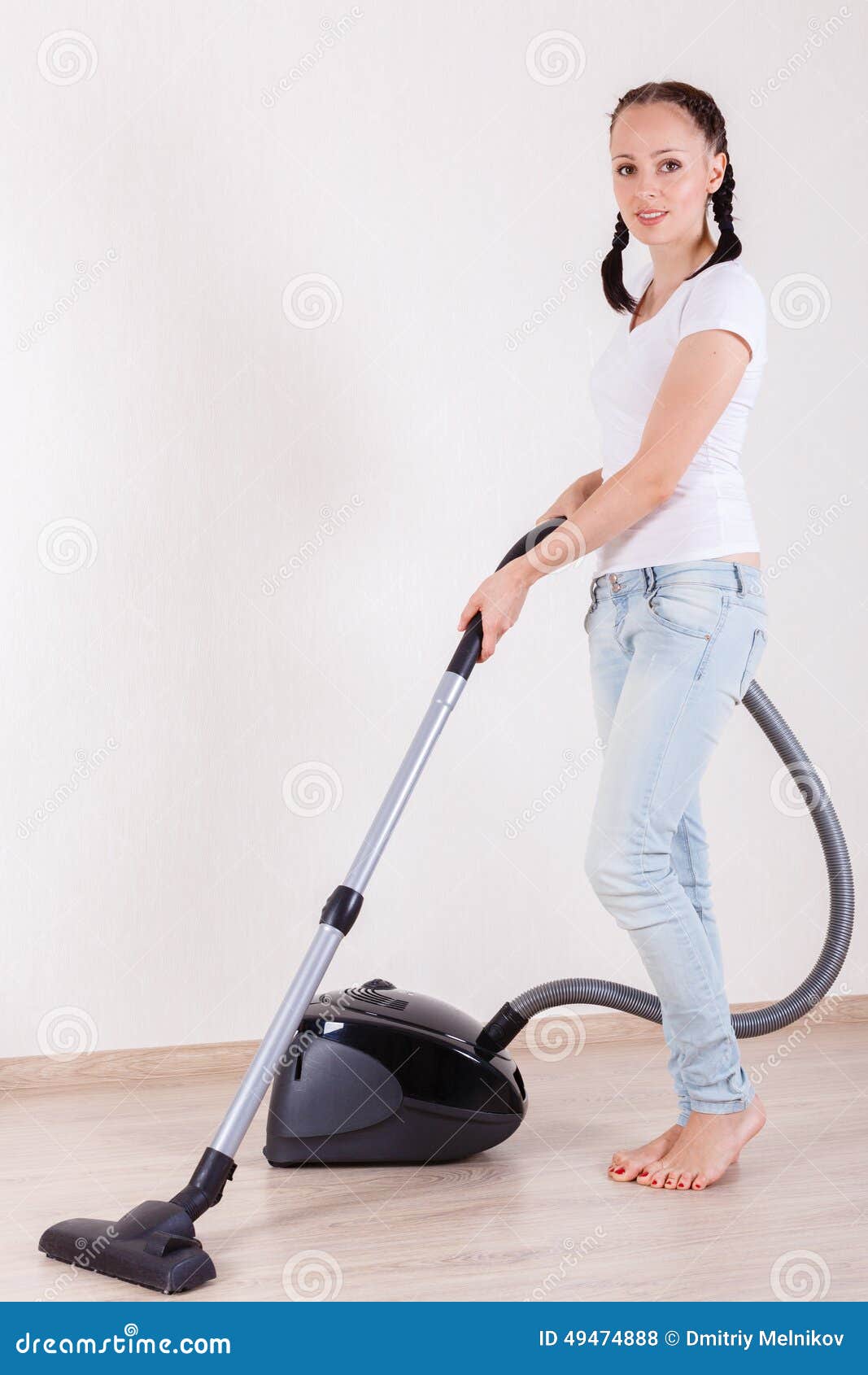 Jeune femme avec l'aspirateur. La jeune femme nettoie le plancher à la maison avec un aspirateur ménage