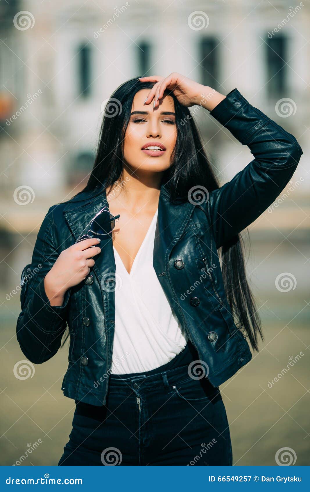 jeune femme de brune de mode dans des lunettes de soleil avec la veste sur la ville image stock