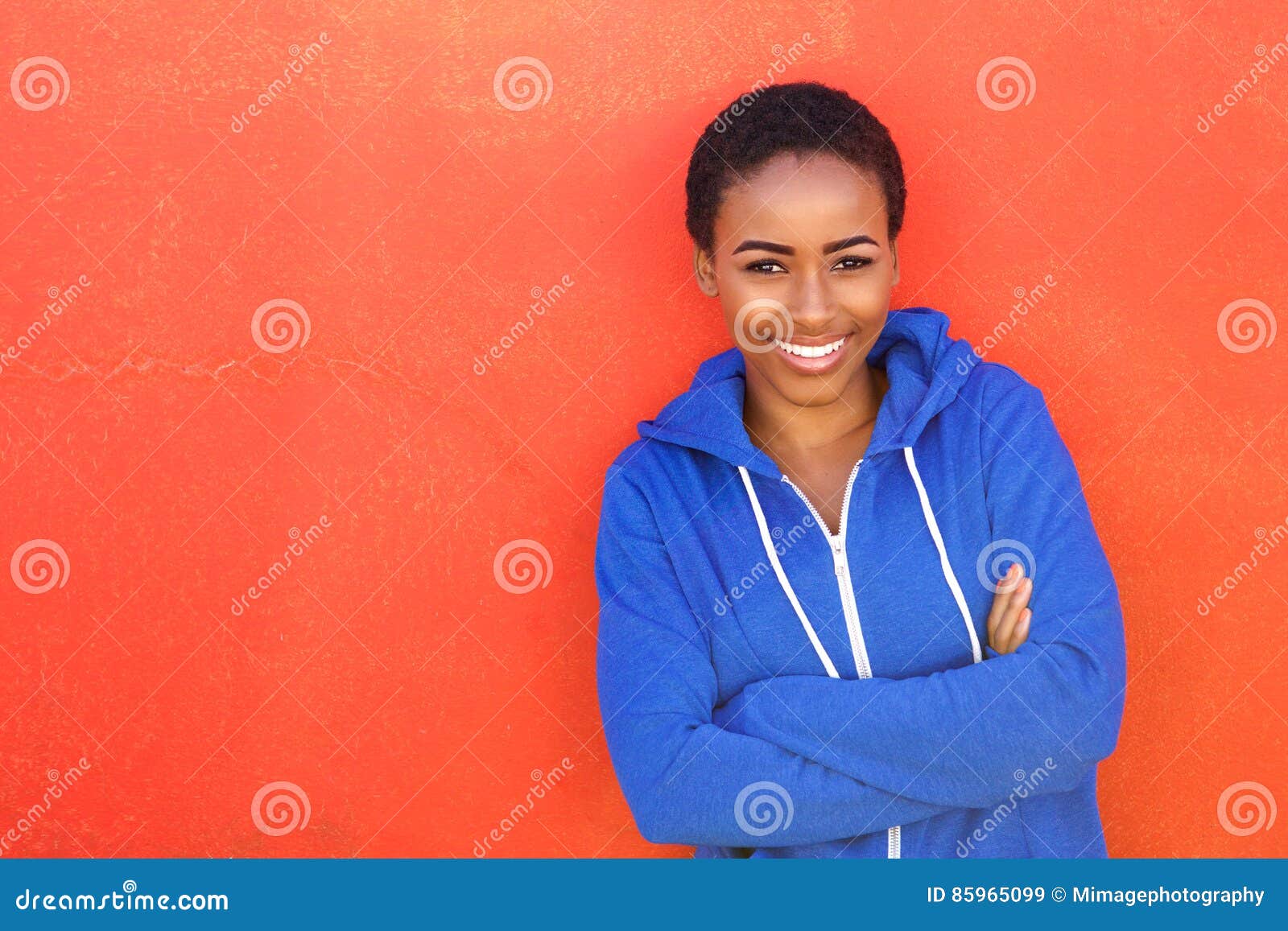 Jeune Femme De Couleur Attirante Souriant Sur Le Fond Rouge Image stock