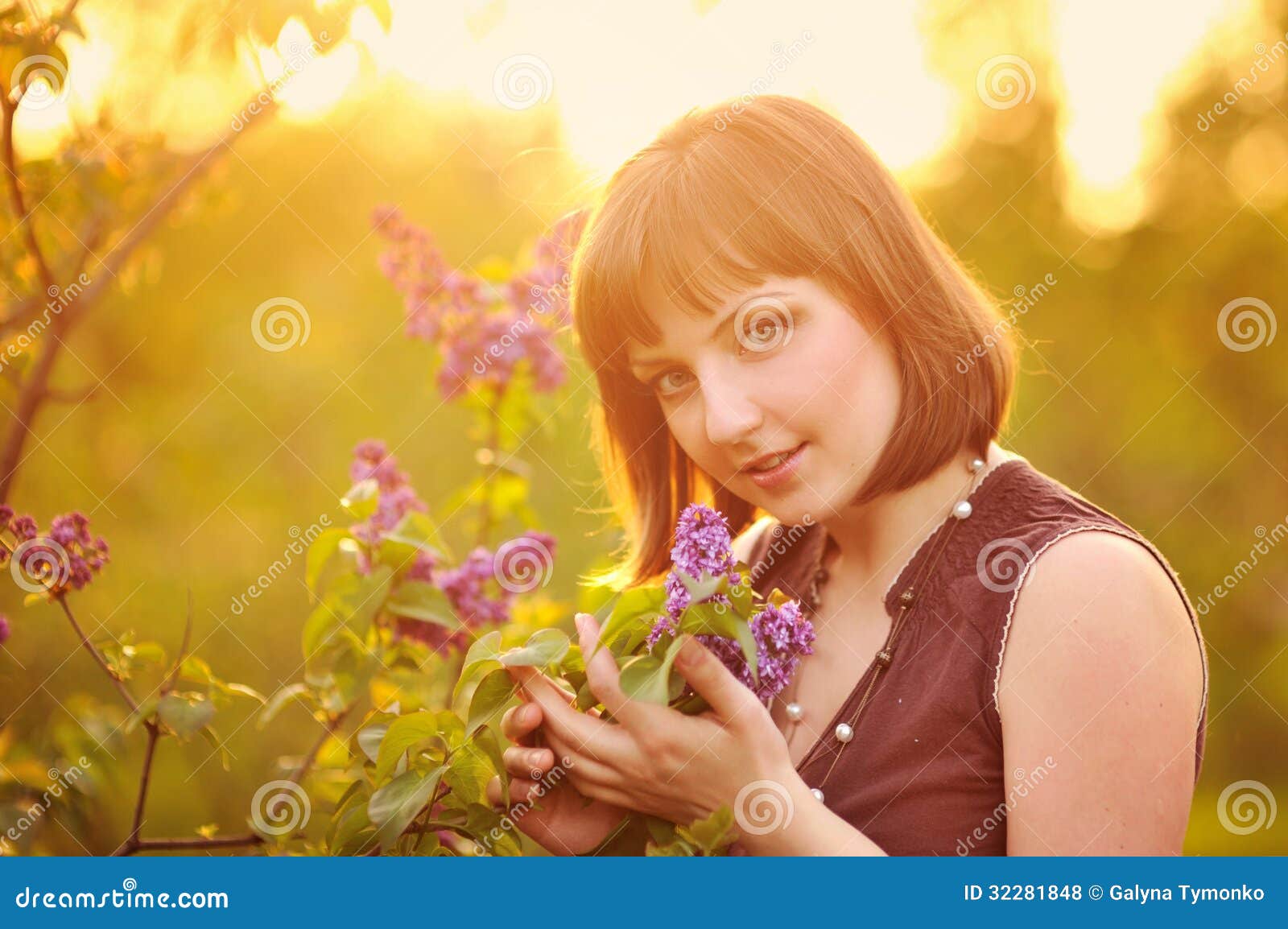 Belle jeune femme en fleurs lilas, dehors portrait