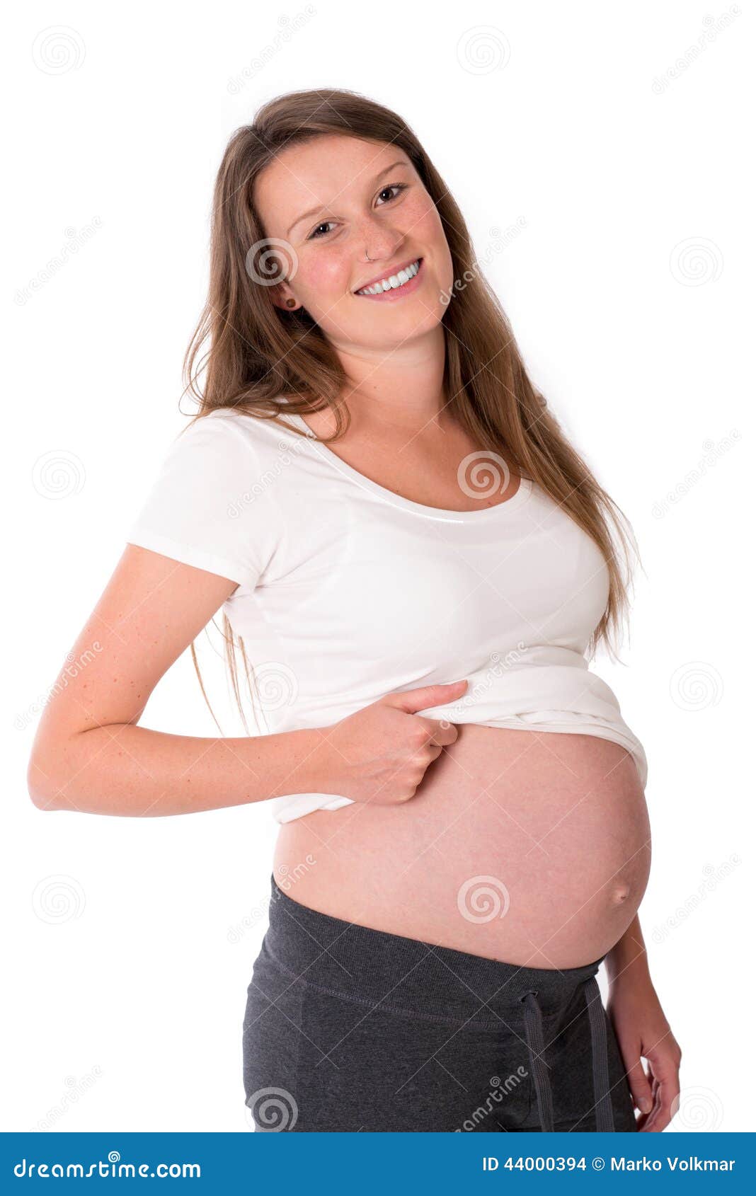 Jeune femme enceinte devant le fond blanc