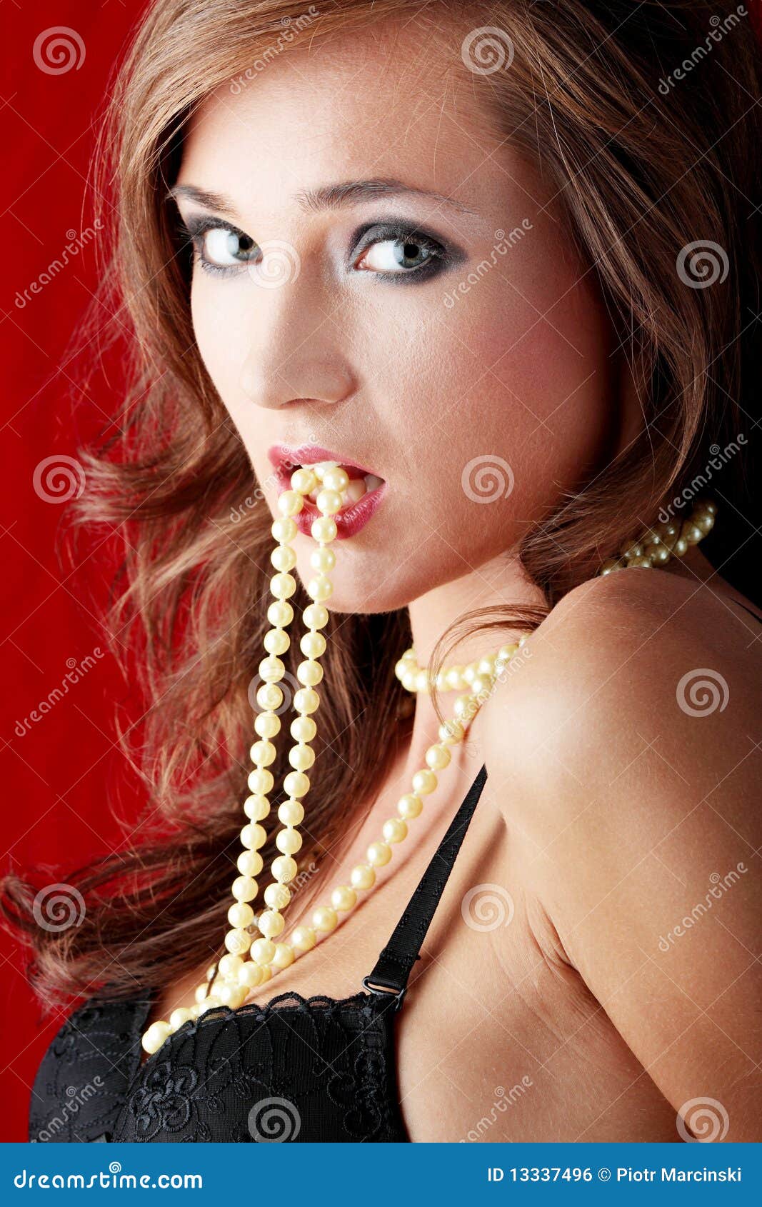 Jeune femme sexy avec un collier de perle au-dessus de fond rouge