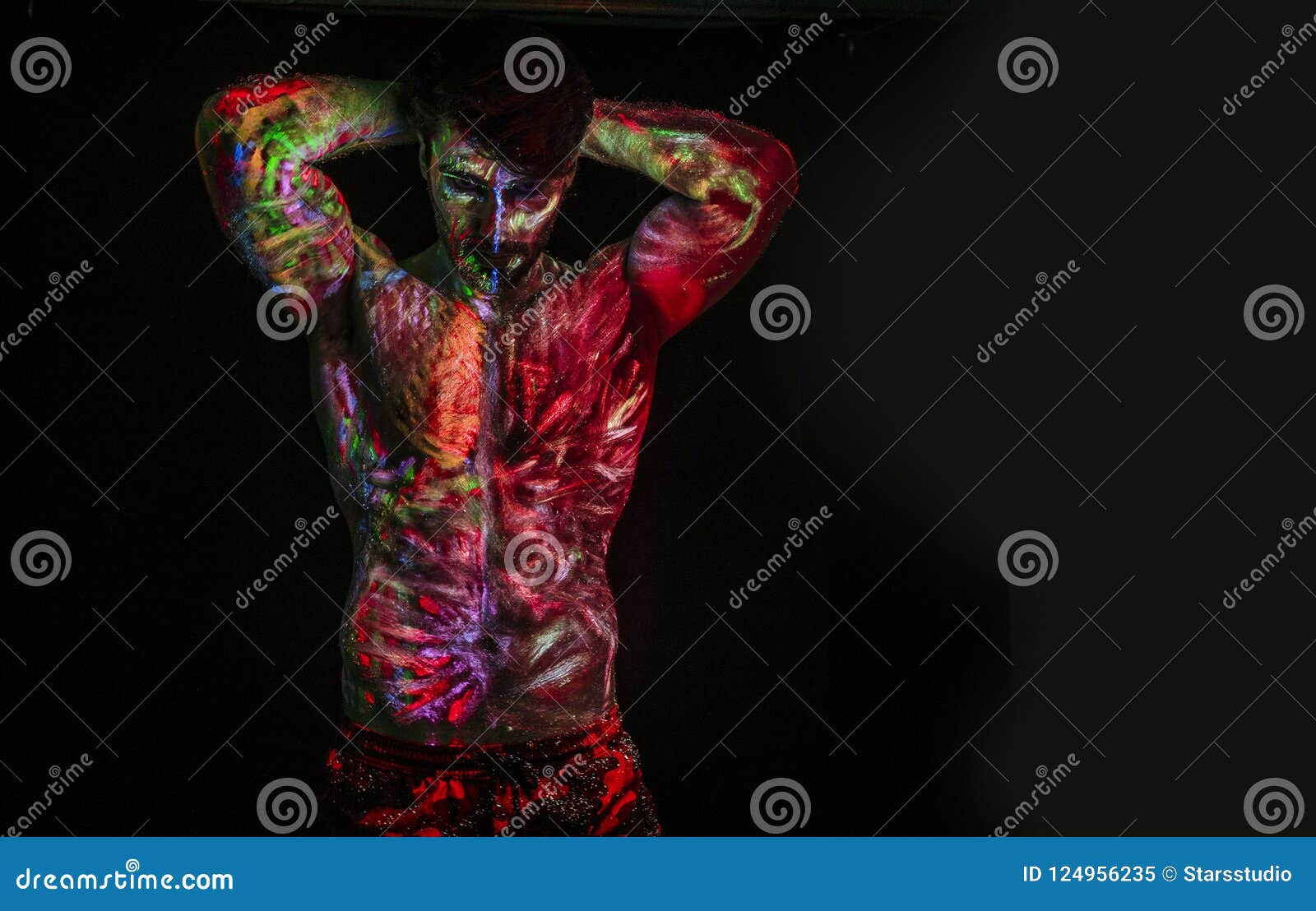 Jeune homme peint à la peinture fluorescente sur le visage et le torse  musclé, dans le studio photo grâce à la lumière UV Photo Stock - Alamy