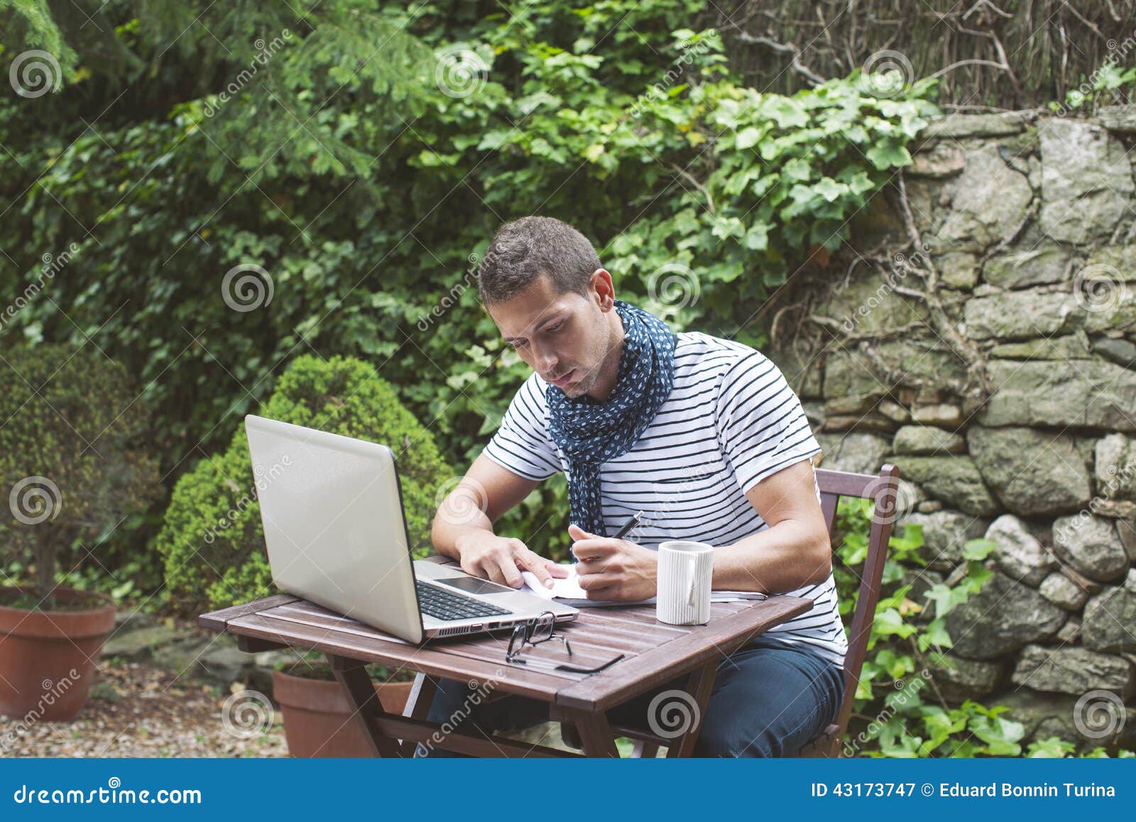 Jeune homme travaillant avec l'ordinateur portable dedans dehors. Homme attirant travaillant dans votre jardin