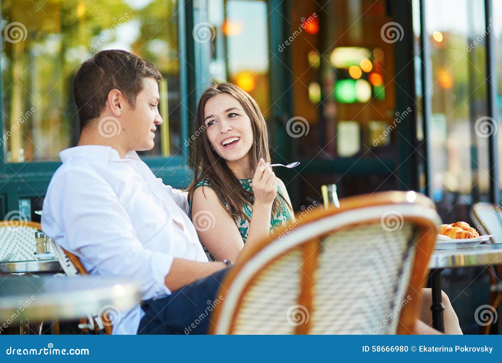 Jeunes couples romantiques en café parisien. Café potable de jeunes couples romantiques et consommation des croissants français traditionnels dans un café extérieur confortable à Paris, France