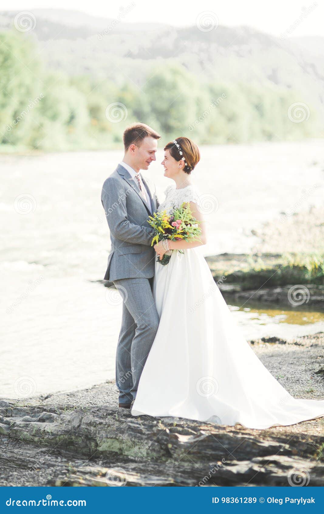 Jeunes mariés tenant le beau bouquet de mariage Pose près de la rivière