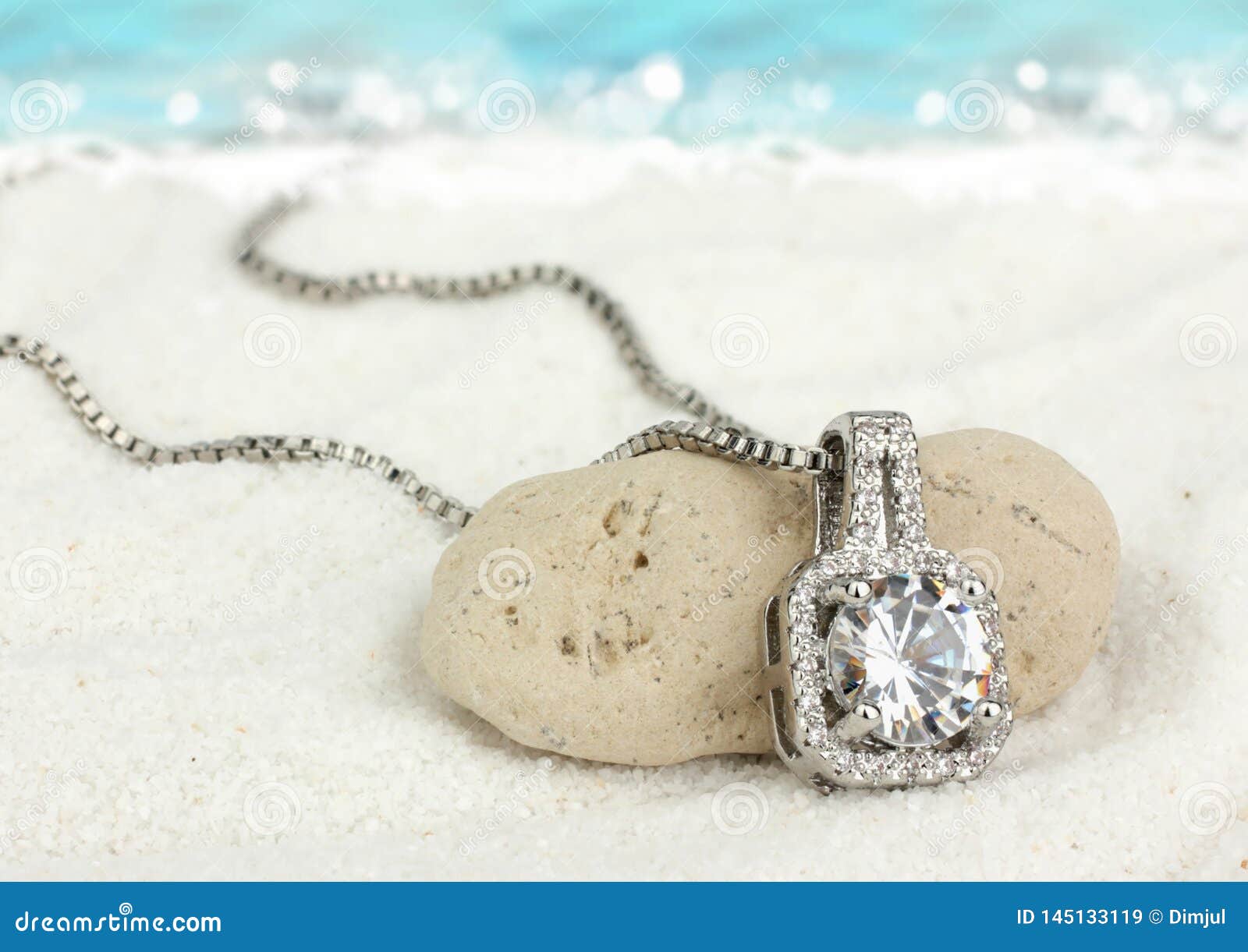 jewelry pendant with big diamond on sand beach as background