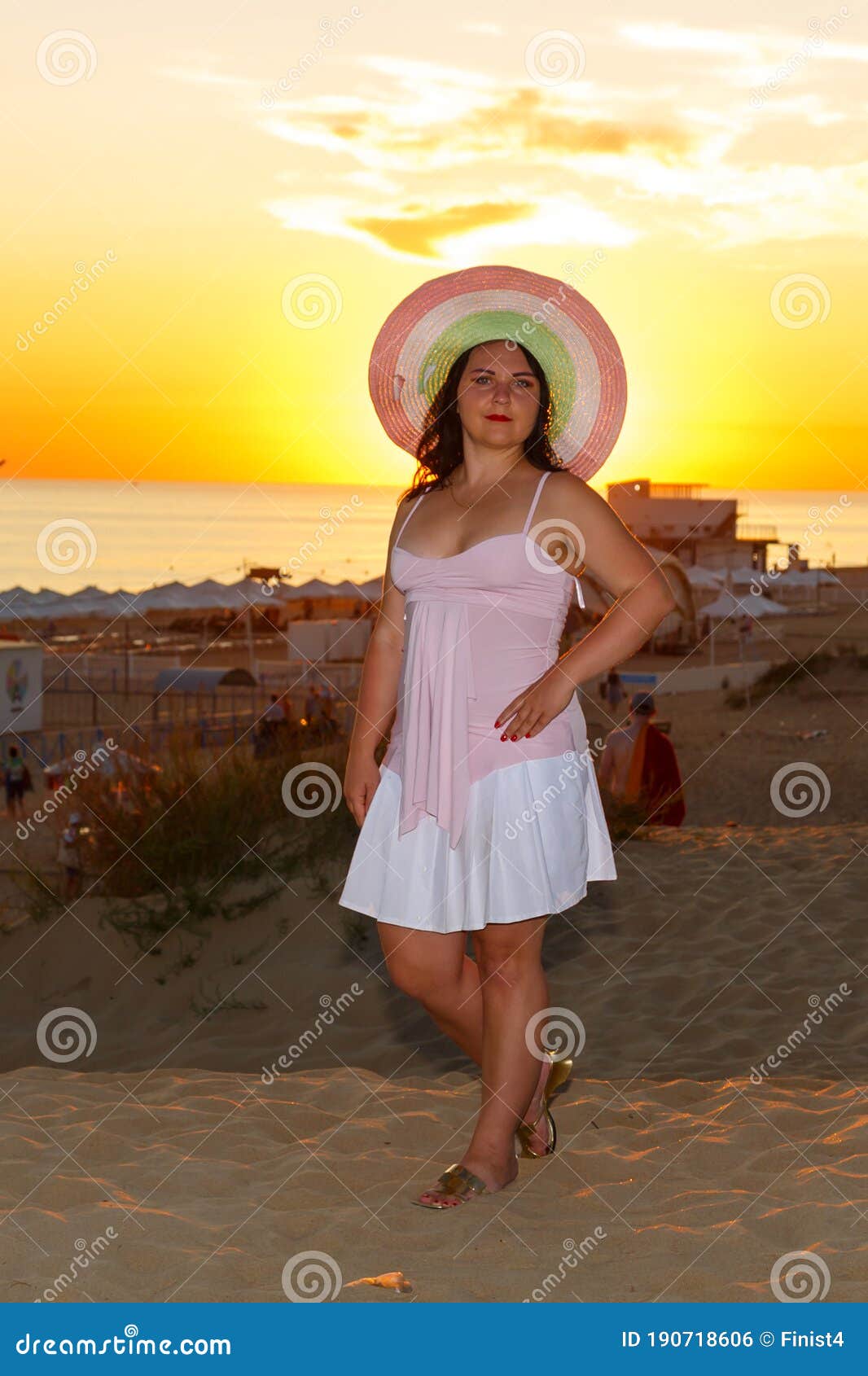 jewish woman in a hat and white dress at sunset on a background of the sea.