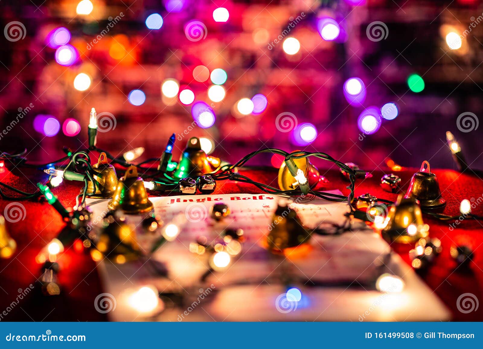jingle bells sheet music lit by christmas lights, surrounded by various bells.  shallow depth of field with heavy bokeh