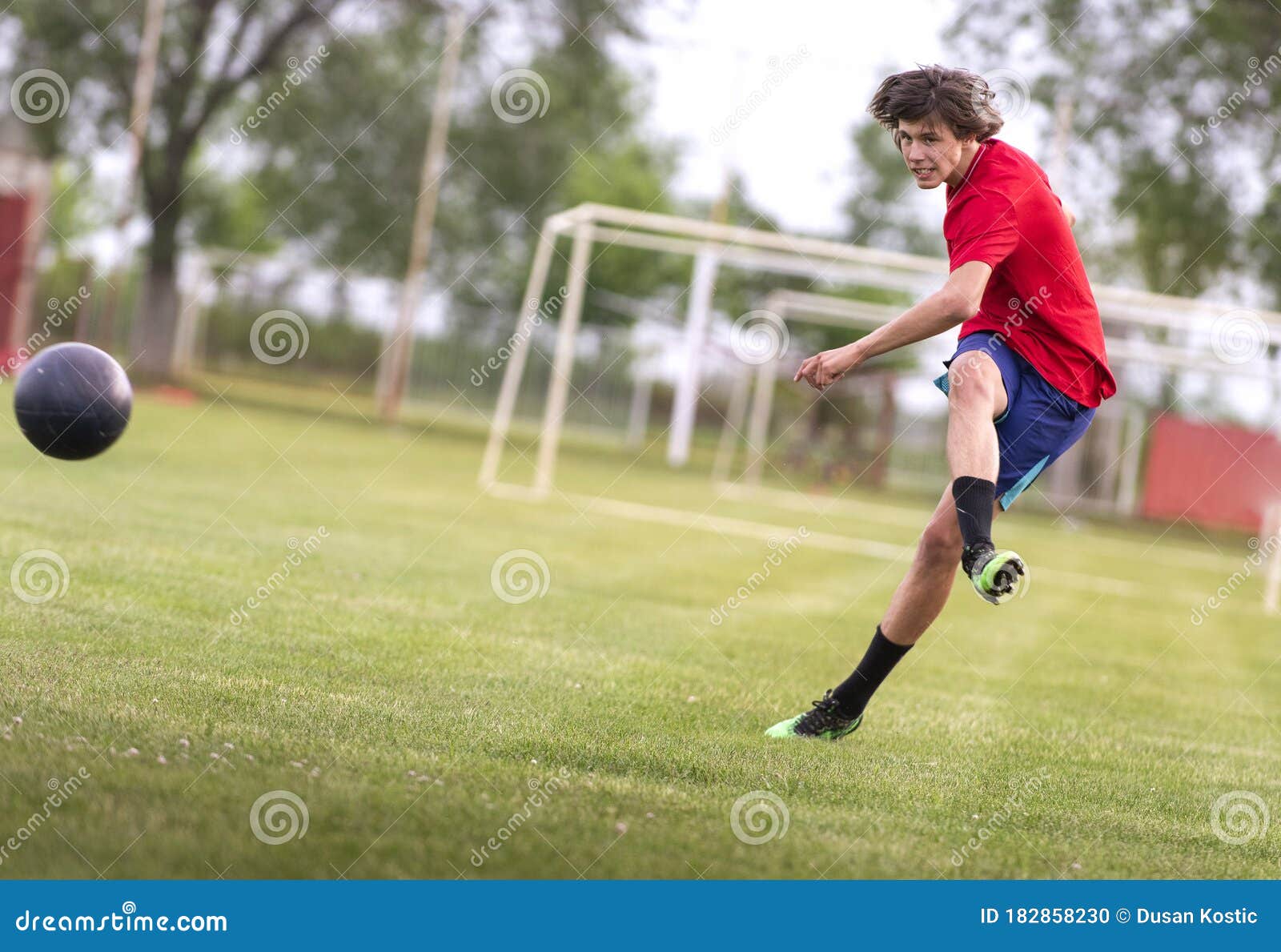 Um jogador de futebol chuta uma bola de futebol em um campo