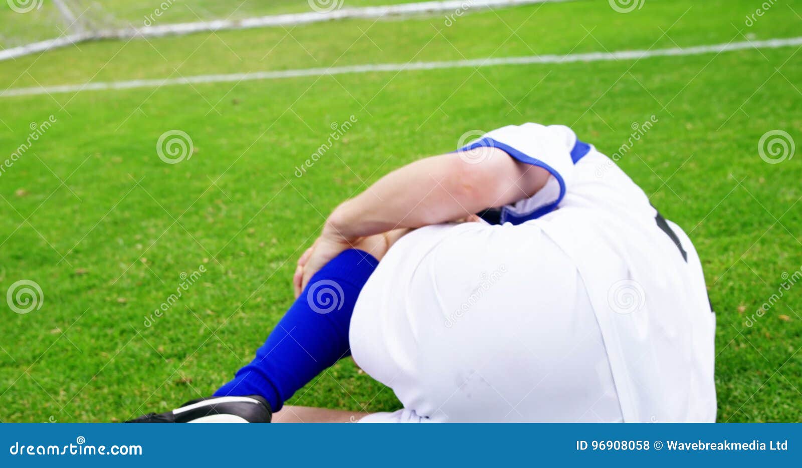 Dois jogadores de futebol masculinos deitado na grama do campo