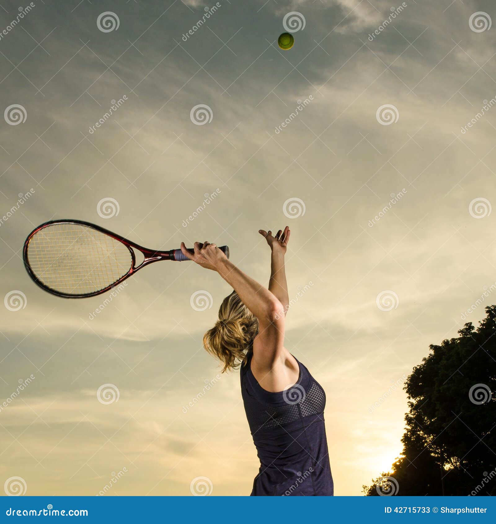 Jogador de tênis fêmea aproximadamente para servir a bola. Imagem de uma mulher que joga o tênis no por do sol