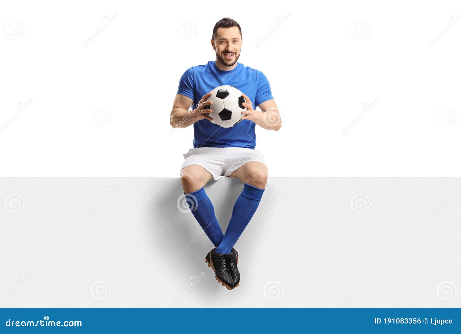 Jogador de futebol forte com bola de futebol e sorrindo em fundo branco  isolado