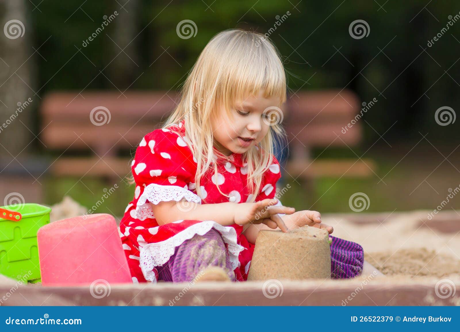 Jogo adorável da menina com os brinquedos na caixa de areia. Jogo adorável da menina com brinquedos