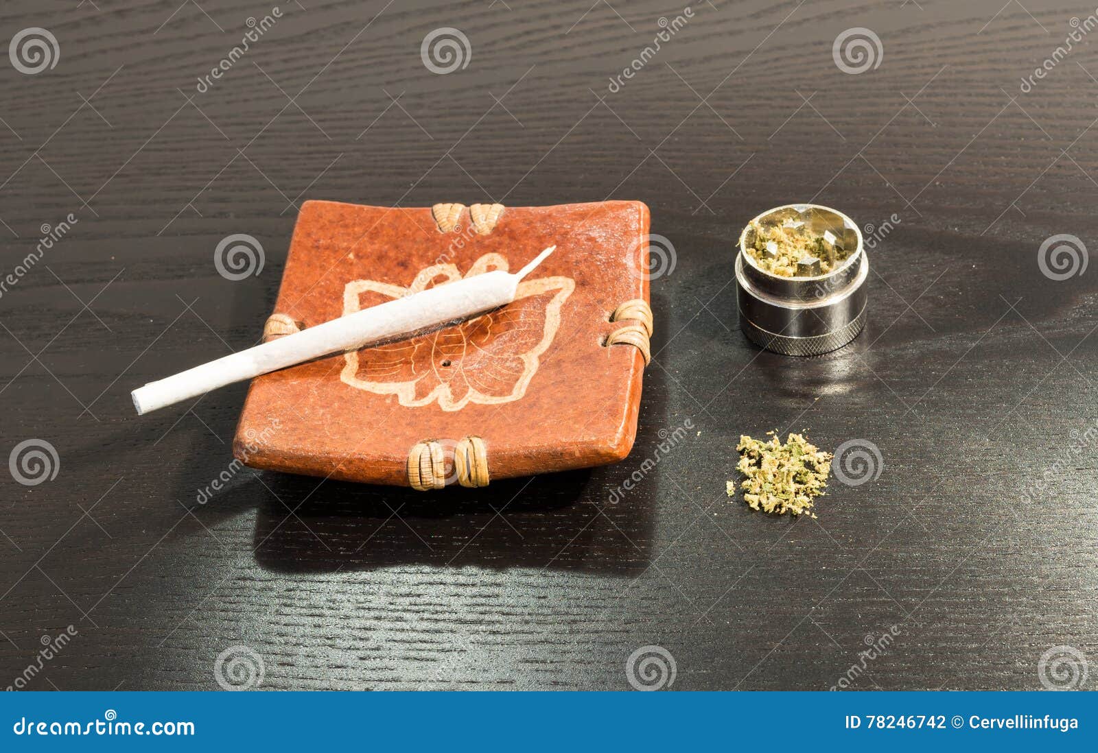Joint in the Ashtray and Metal Grinder with Marijuana Stock Photo