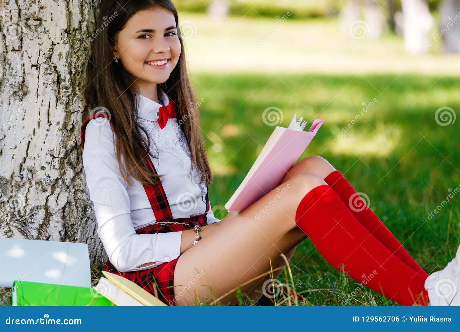Jong Schoolmeisje in School Eenvormige Zitting Op Het Gras Onder Een ...