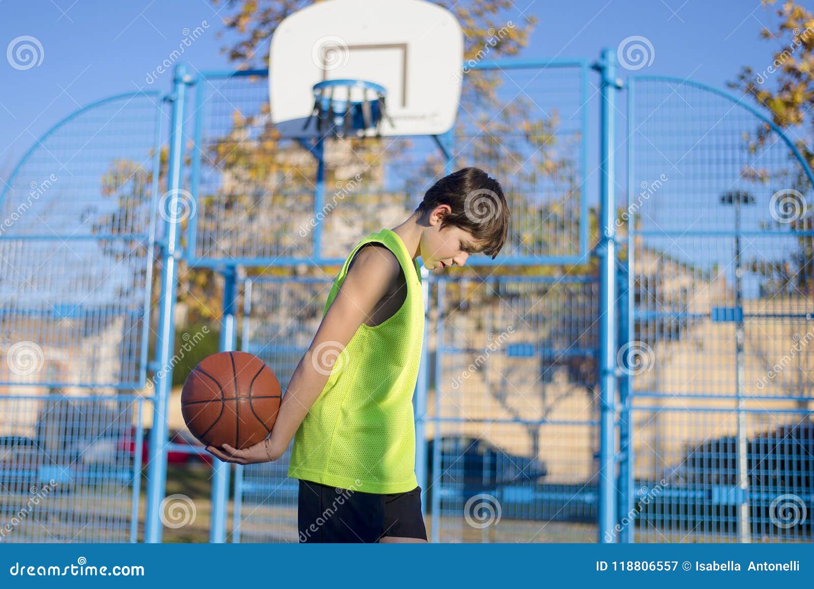 Jonge basketbalspeler die zich op het hof bevinden die gele sleeveless dragen