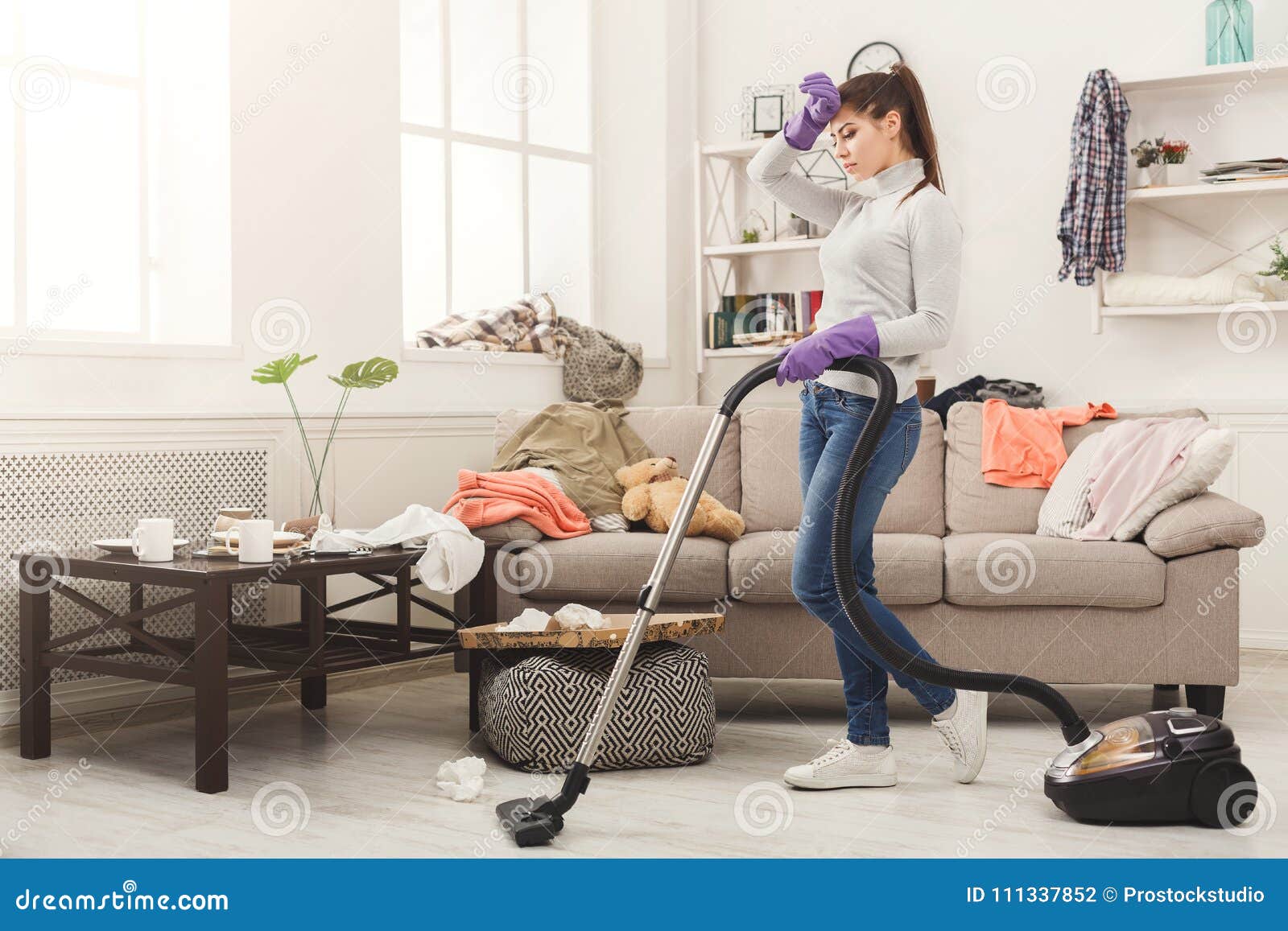 Jonge die vrouw van de lente schoonmakend huis wordt vermoeid, wassende vloer met stofzuiger in slordige ruimte, exemplaarruimte