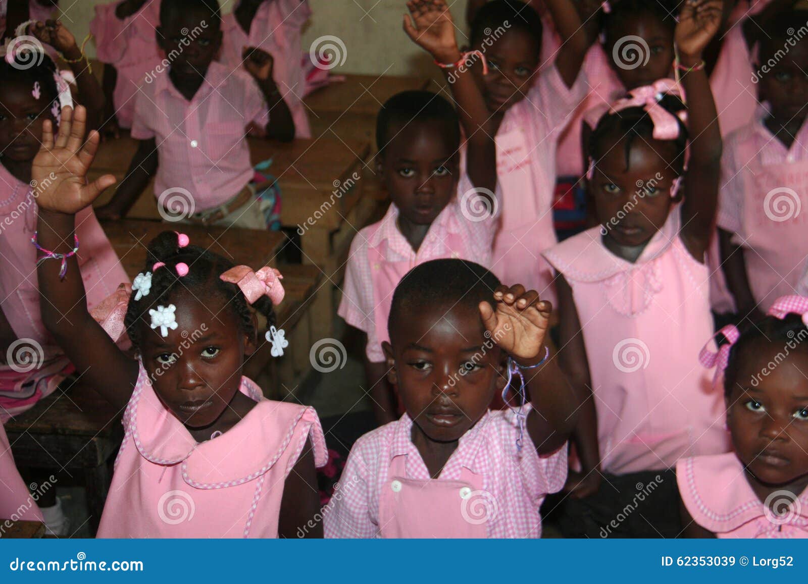 Jonge Haïtiaanse schoolmeisjes en jongens in klaslokaal op school. Jonge Katholieke Haïtiaanse schoolkinderen die hun vriendschapsarmbanden in klaslokaal tonen op school in landelijke Petit Bourg DE Port Margot