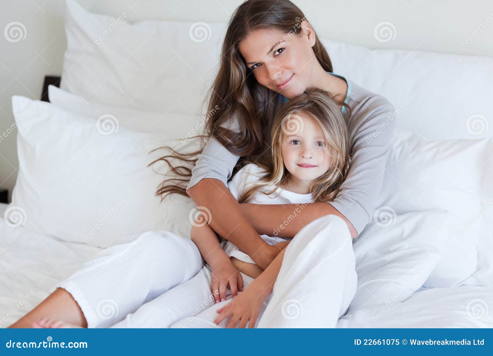 Jonge Moeder En Haar Dochter Het Stellen Op Een Bed Stock