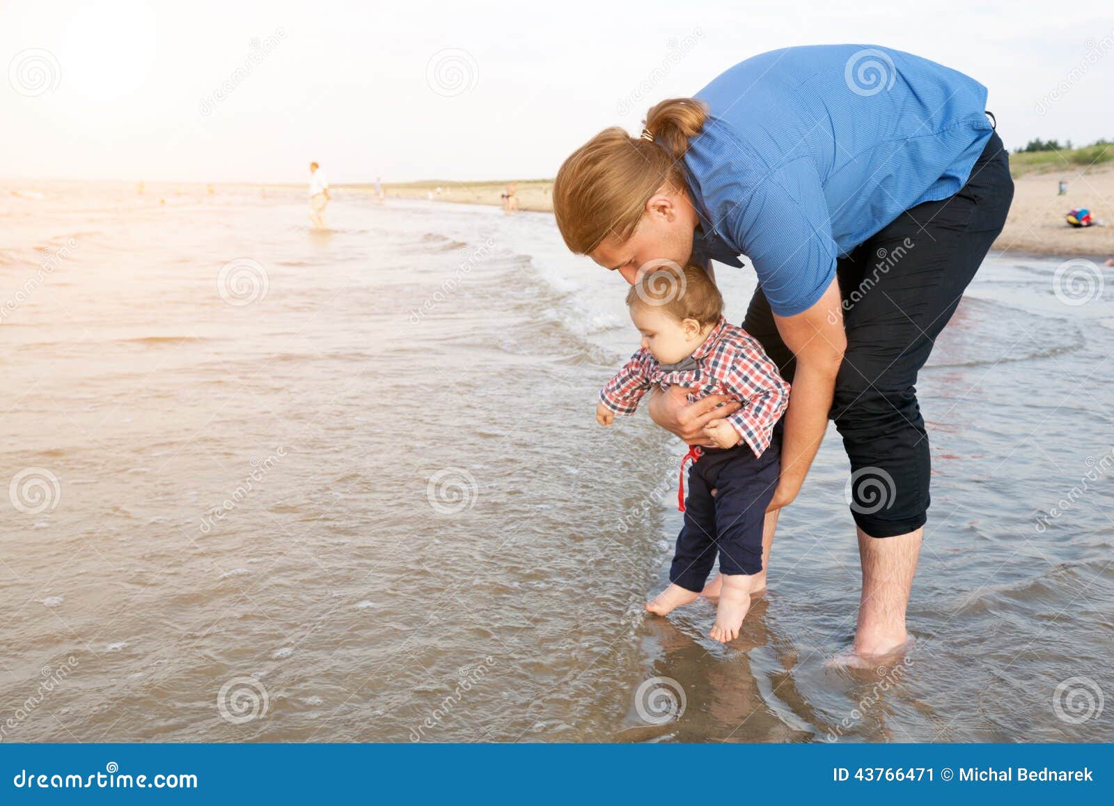 Jonge vader die zijn kind over zeewater houden. Jonge vader die samen zijn kind over zeewater houden die pret hebben Zoon en ouderband