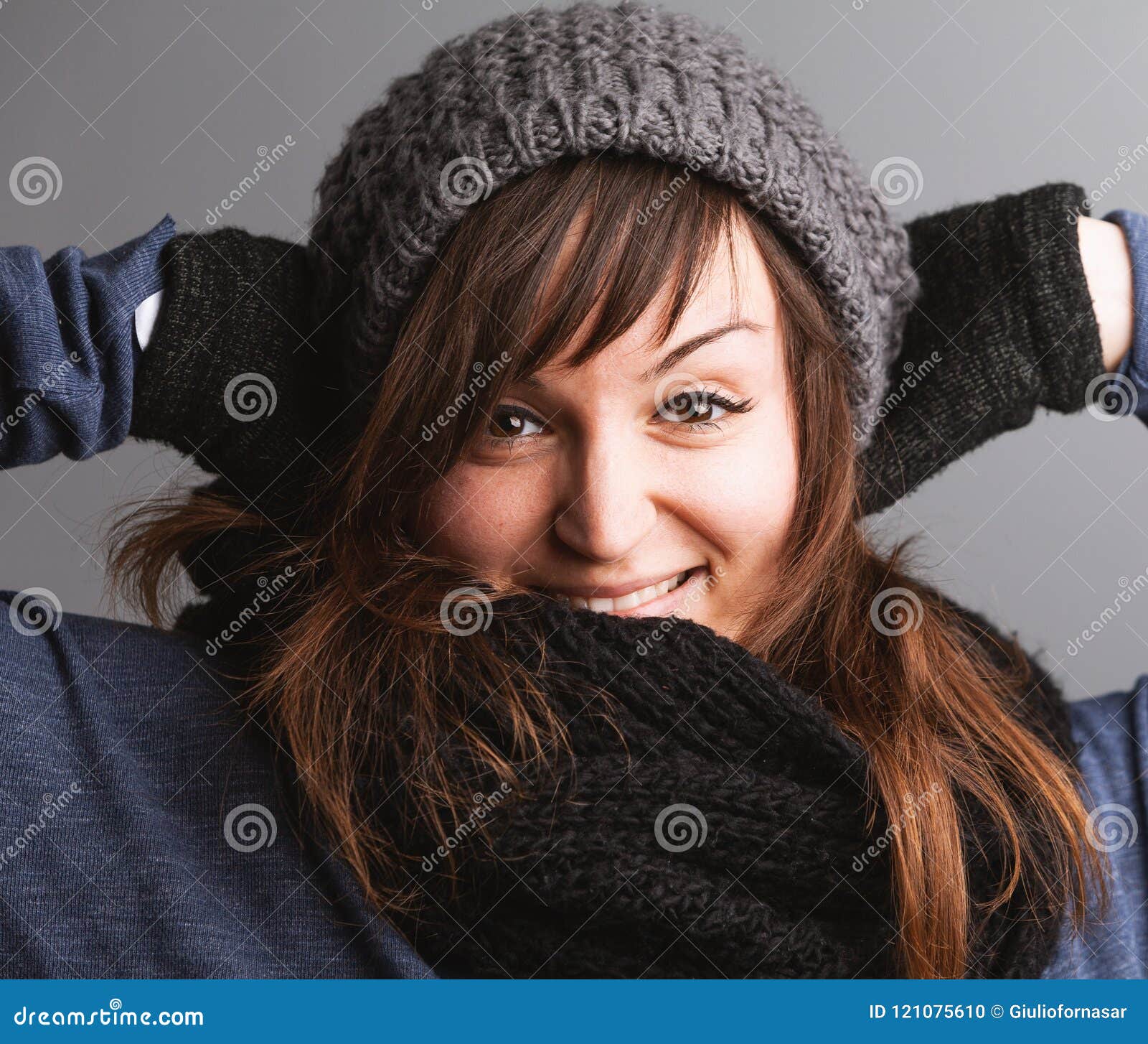 Jonge vrolijke vrouw die de winterkleding dragen. Het portret van jonge vrolijke vrouw die de winter dragen breide hoed met sjaal en handschoenen
