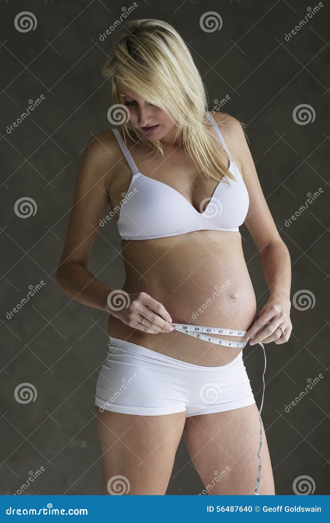 Jonge zwangere vrouw die haar buik meten. Jonge zwangere vrouw die haar buik met het meten van band meten