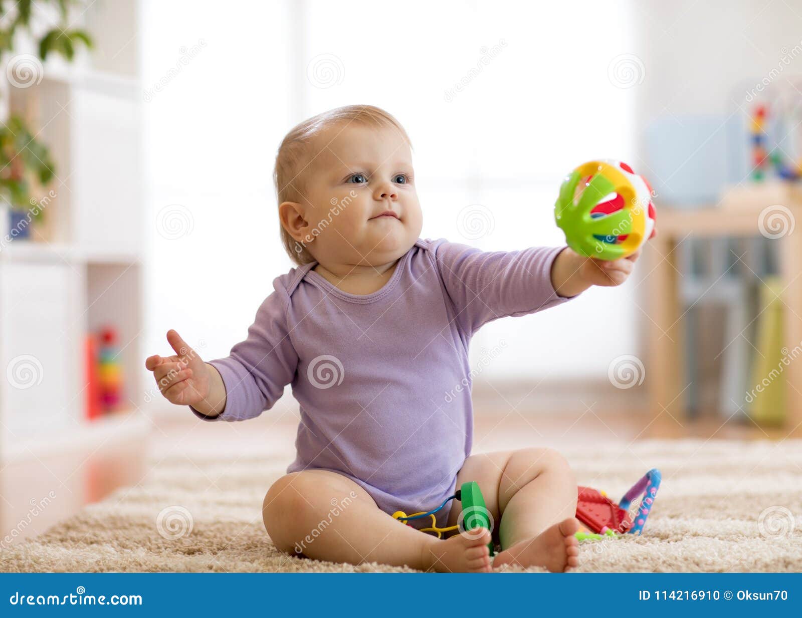 Jouer Infantile Et Jouet D'enfant En Bas âge De Bébé D'enfant Dans Sa Main  Sur Le Plancher Photo stock - Image du beau, bille: 114216910