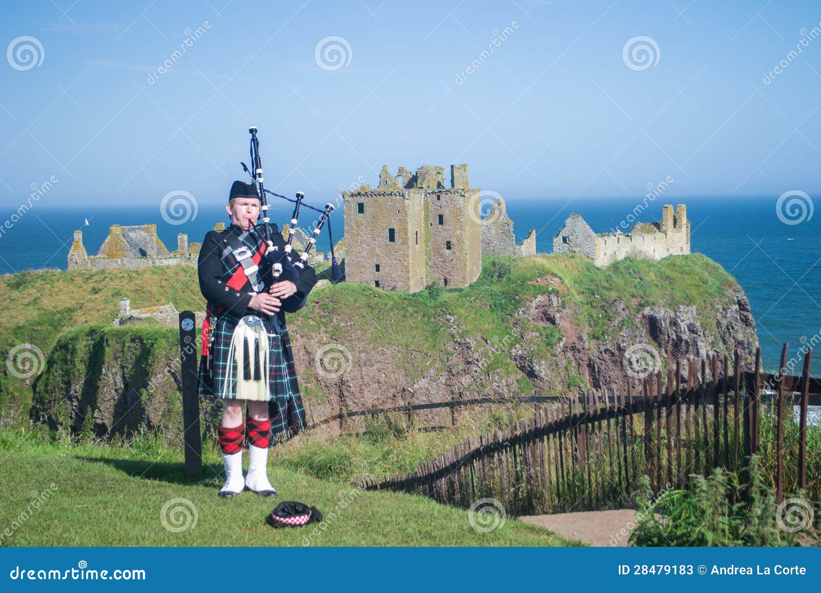 Joueur de pipeau écossais au château de Dunnottar, Aberdeenshire, Ecosse. Il joue la pipe avec le château à l'arrière-plan