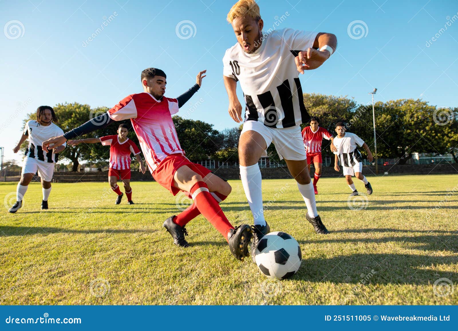 Joueurs Multiraciaux Courir Et Frapper Le Ballon De Football Pendant Le  Match Dans Le Terrain De Jeu Contre Ciel Clair Image stock - Image du  copie, actif: 251511005