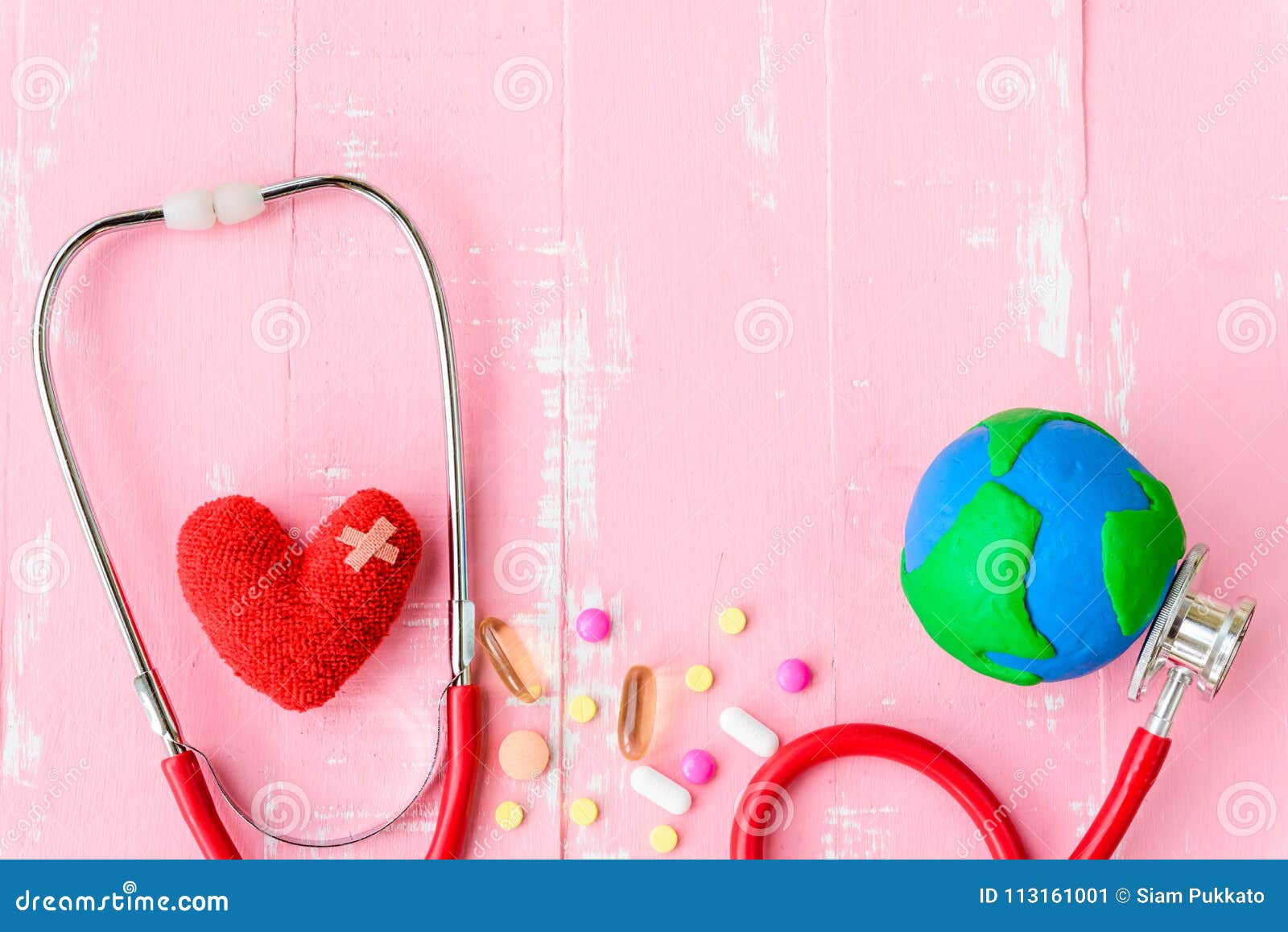 Jour de santé du monde, soins de santé et concept médical Coeur rouge avec le stéthoscope, le globe fait main, le thermomètre et la pilule jaune sur le fond en bois blanc et rose en pastel