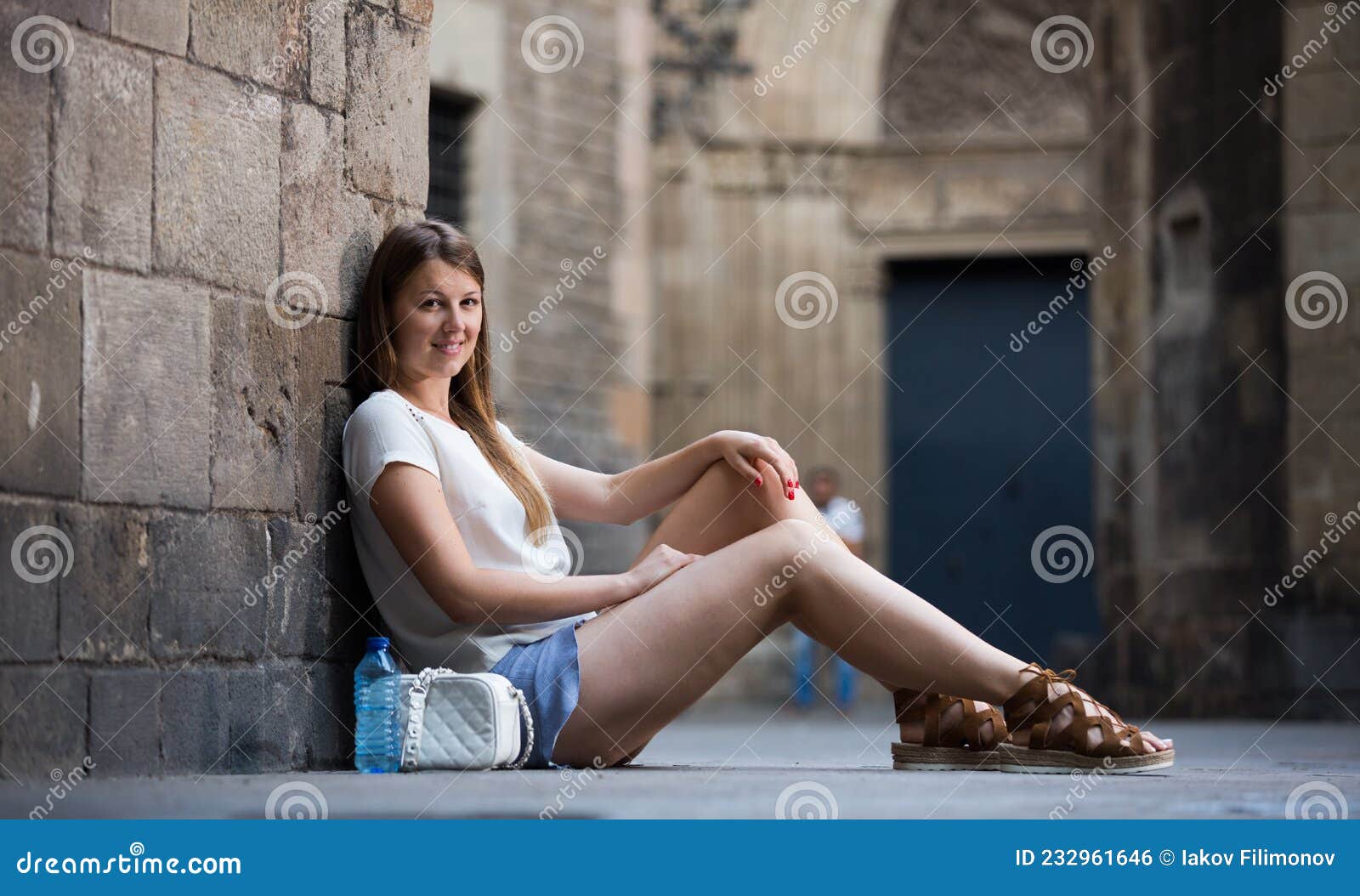 Duas lindas meninas sentadas em frente a um velho muro de pedra